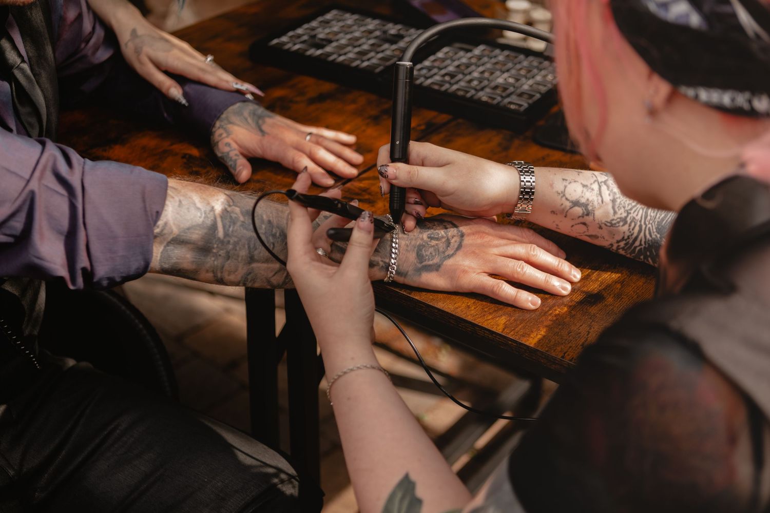Tattoo artist applying detailed ink designs on a client's arm in a professional tattoo studio setting.