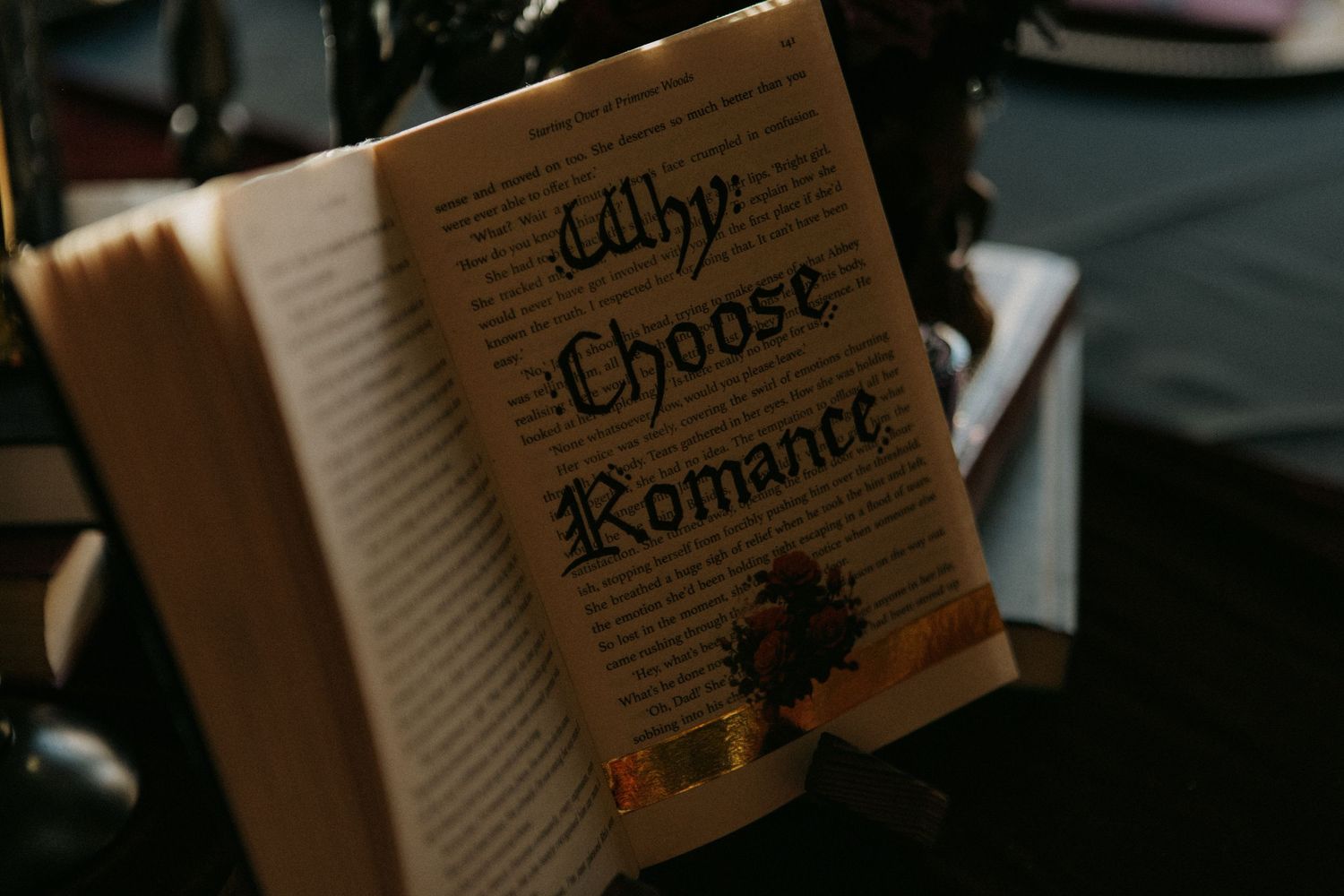 Open book with gothic lettering reading Why Choose Romance displayed on a decorative stand.