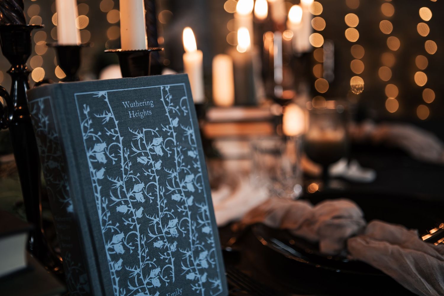 A copy of Wuthering Heights book displayed among lit candles and bokeh lights in a moody, atmospheric setting.