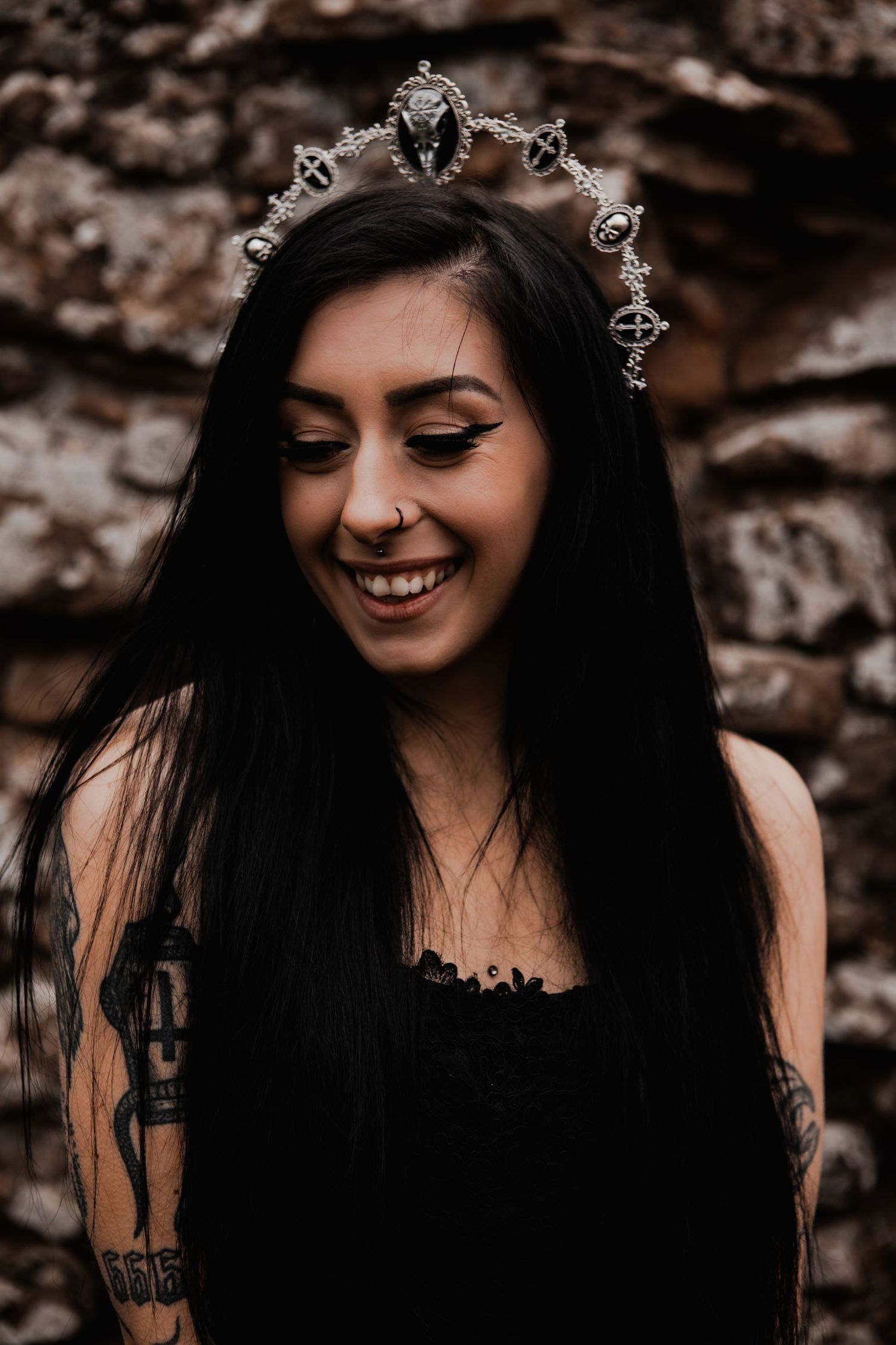 A gothic-styled portrait features a person wearing an ornate crown against a stone wall.