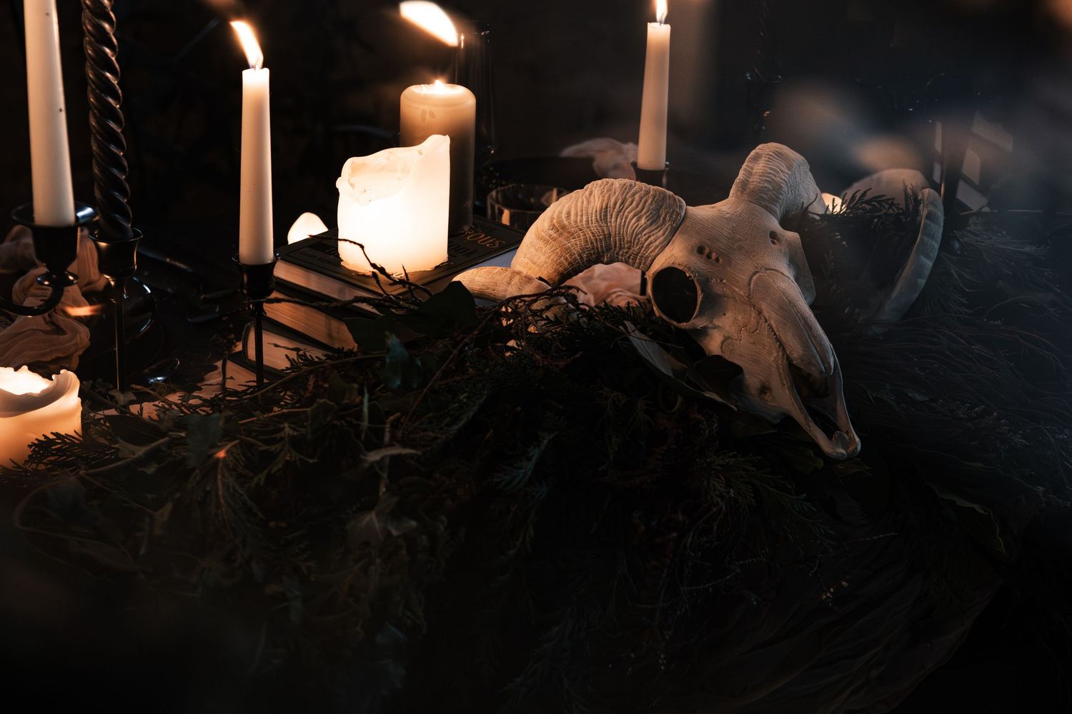 Dark occult altar with ram skull, white candles, and mystical decorations in a dimly lit setting.