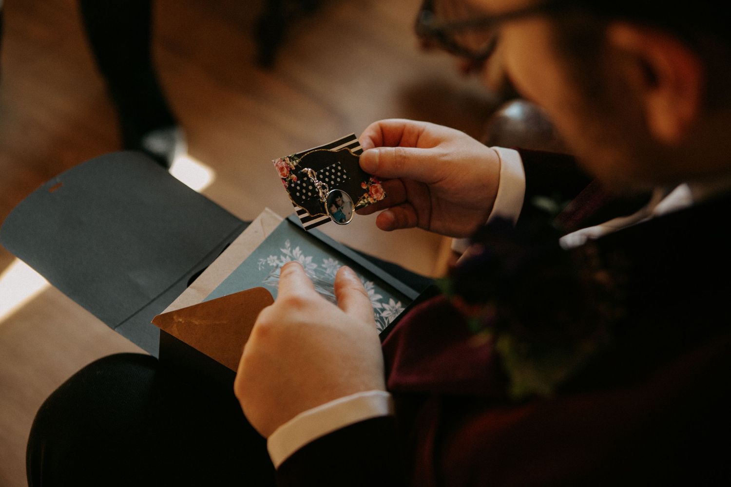 Someone wearing a suit looks at a credit card in their hands while sitting at a table.