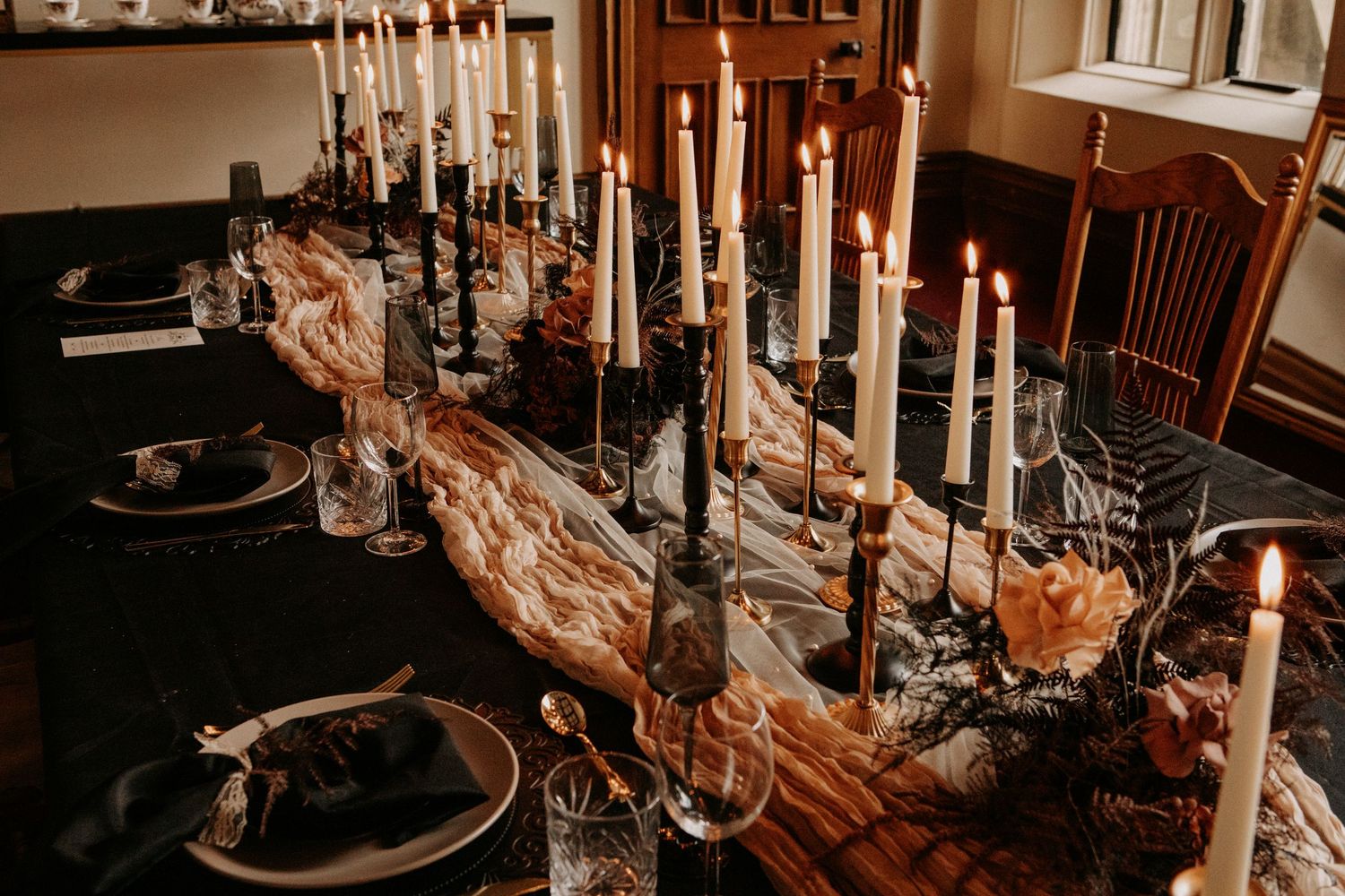 Elegant gothic wedding tablescape with tall black and white candles and moody florals.