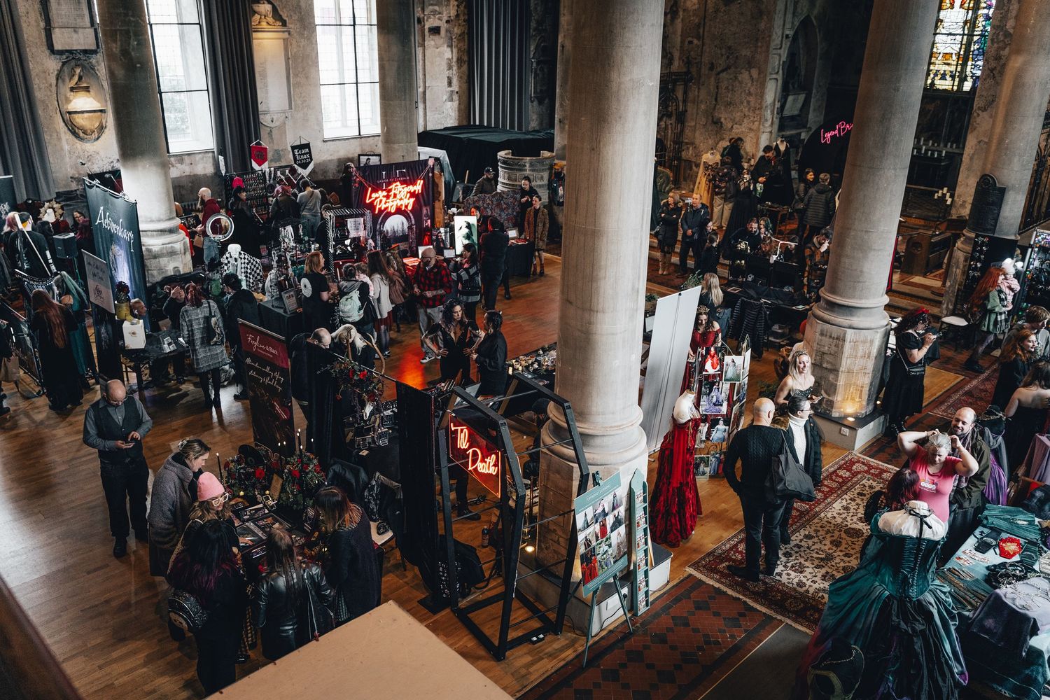Overhead view of a gothic wedding fair inside a historic church venue with vendors.