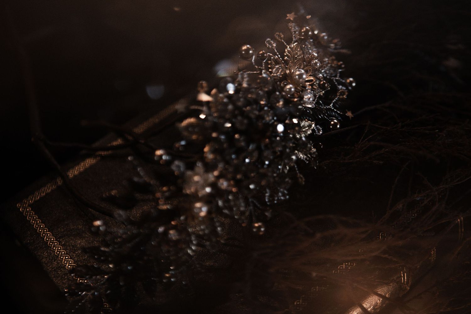 Dark ornate crystal and beaded bridal tiara crown with intricate floral design on dark background.