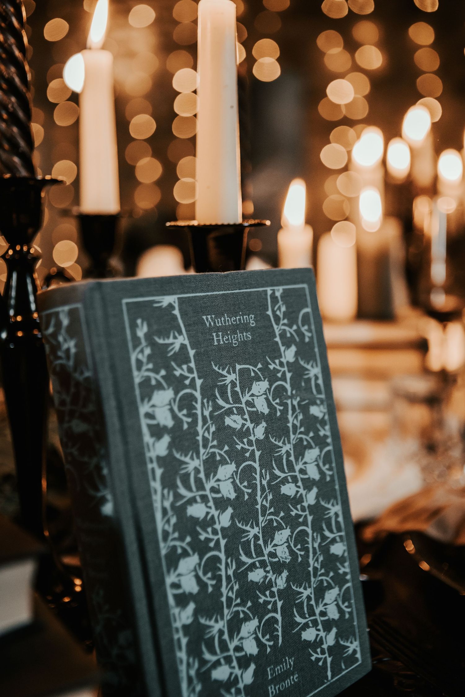 A copy of Wuthering Heights by Emily Bronte displayed among glowing candles and bokeh lights.