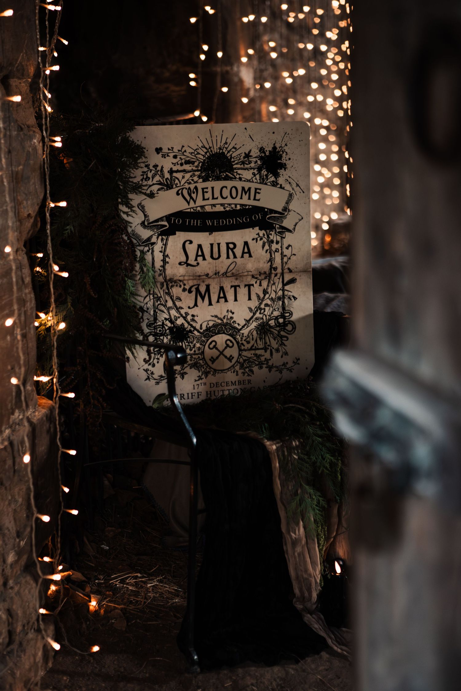 Welcome sign for Laura and Matt's wedding framed by warm fairy lights on a brick wall.