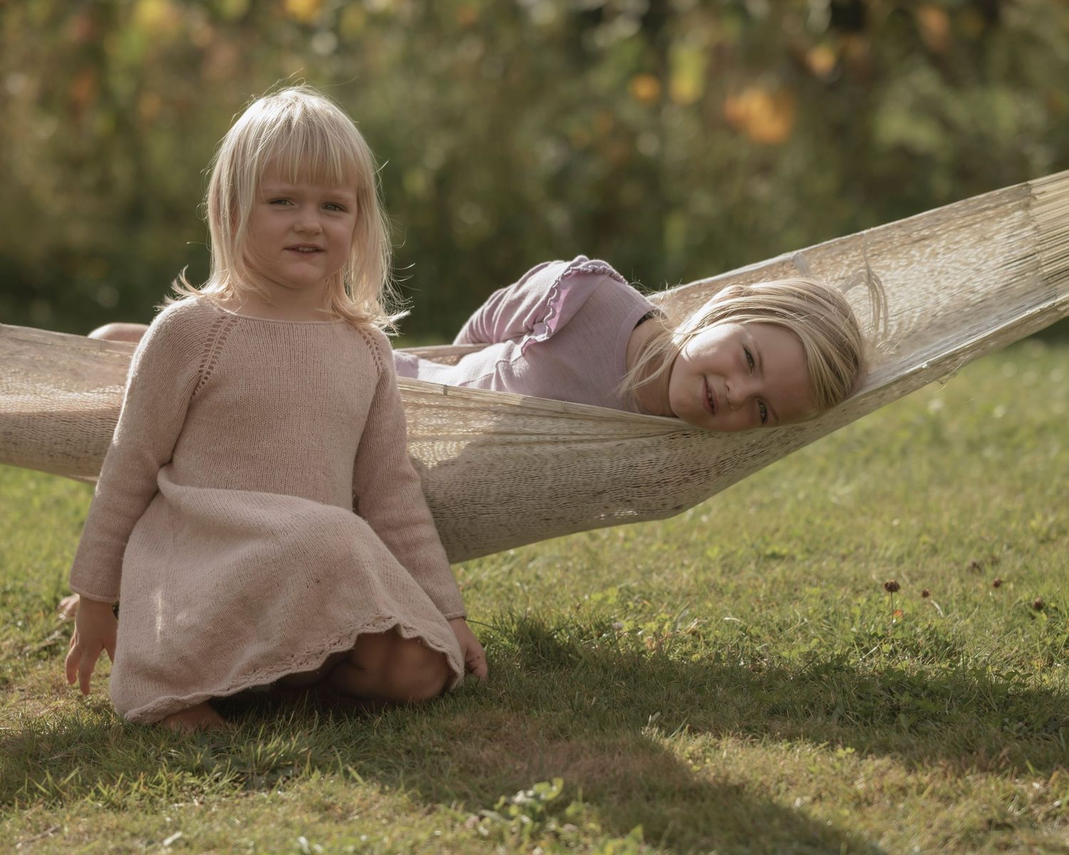 To piger leger og slapper af i en hængekøje under familiefotografering udendørs.
