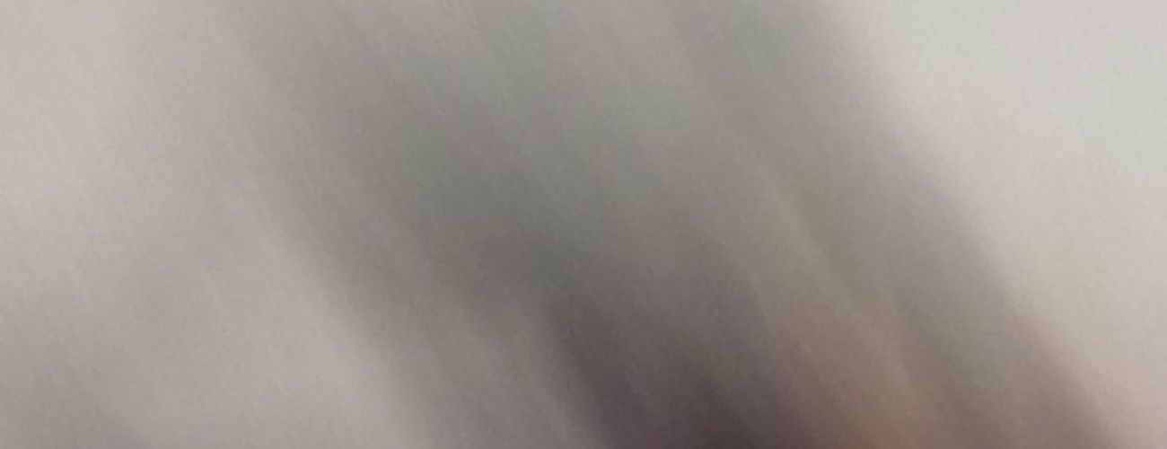 Abstract blurred gray and beige motion blur background texture with soft diagonal light streaks.