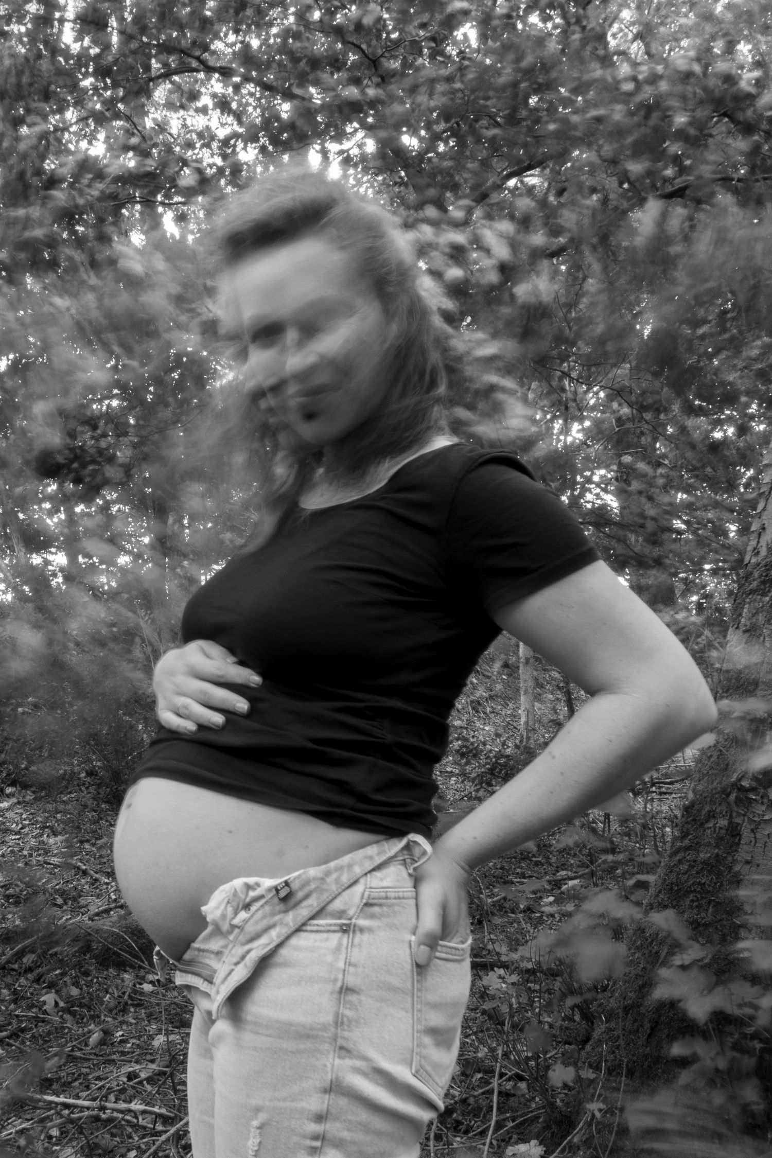 Gravid kvinde viser sin mave under sort-hvid gravidfotografering nær Holstebro.