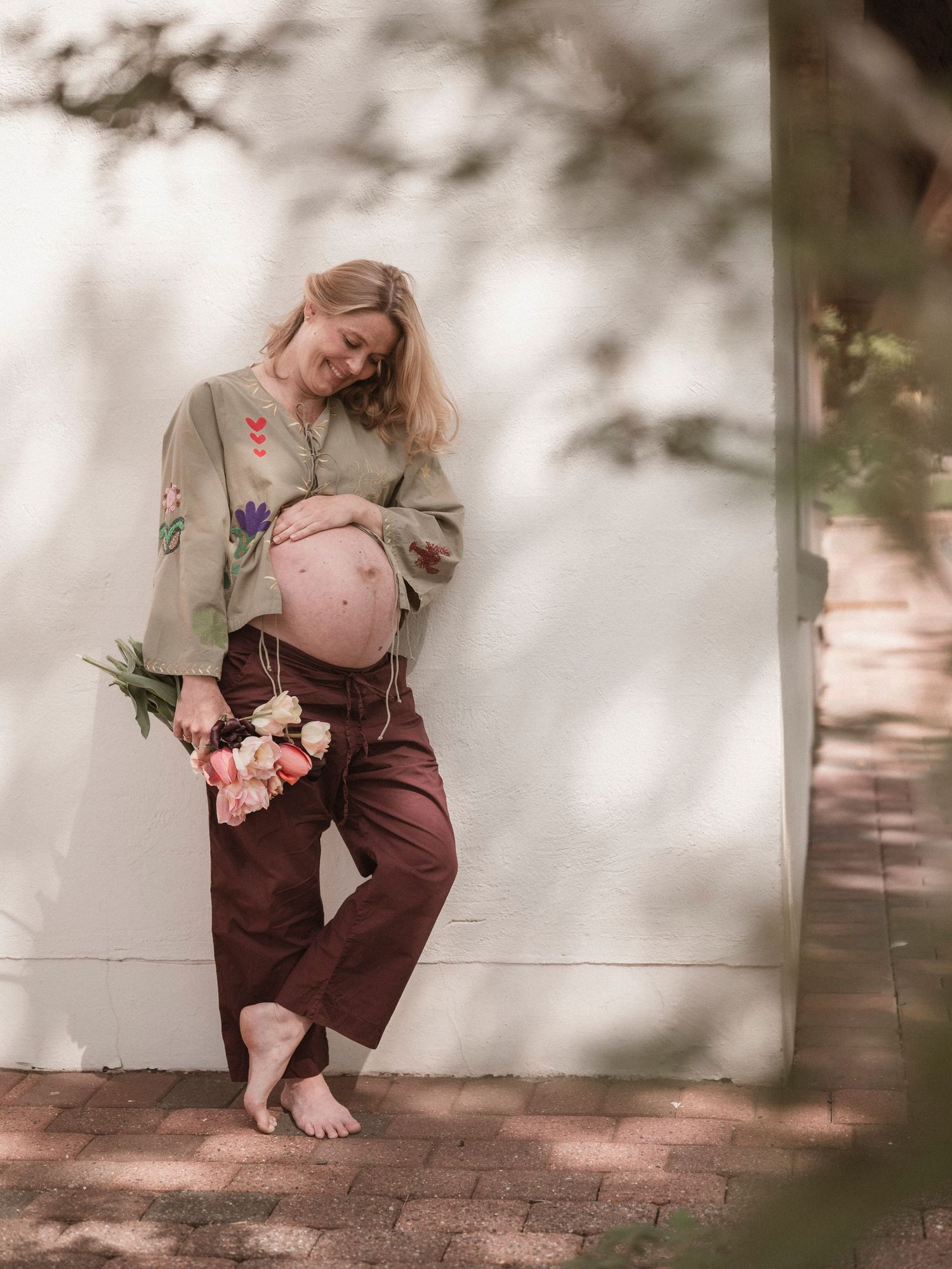 Gravid kvinde med lyserøde tulipaner under gravidfotografering udendørs nær Holstebro.