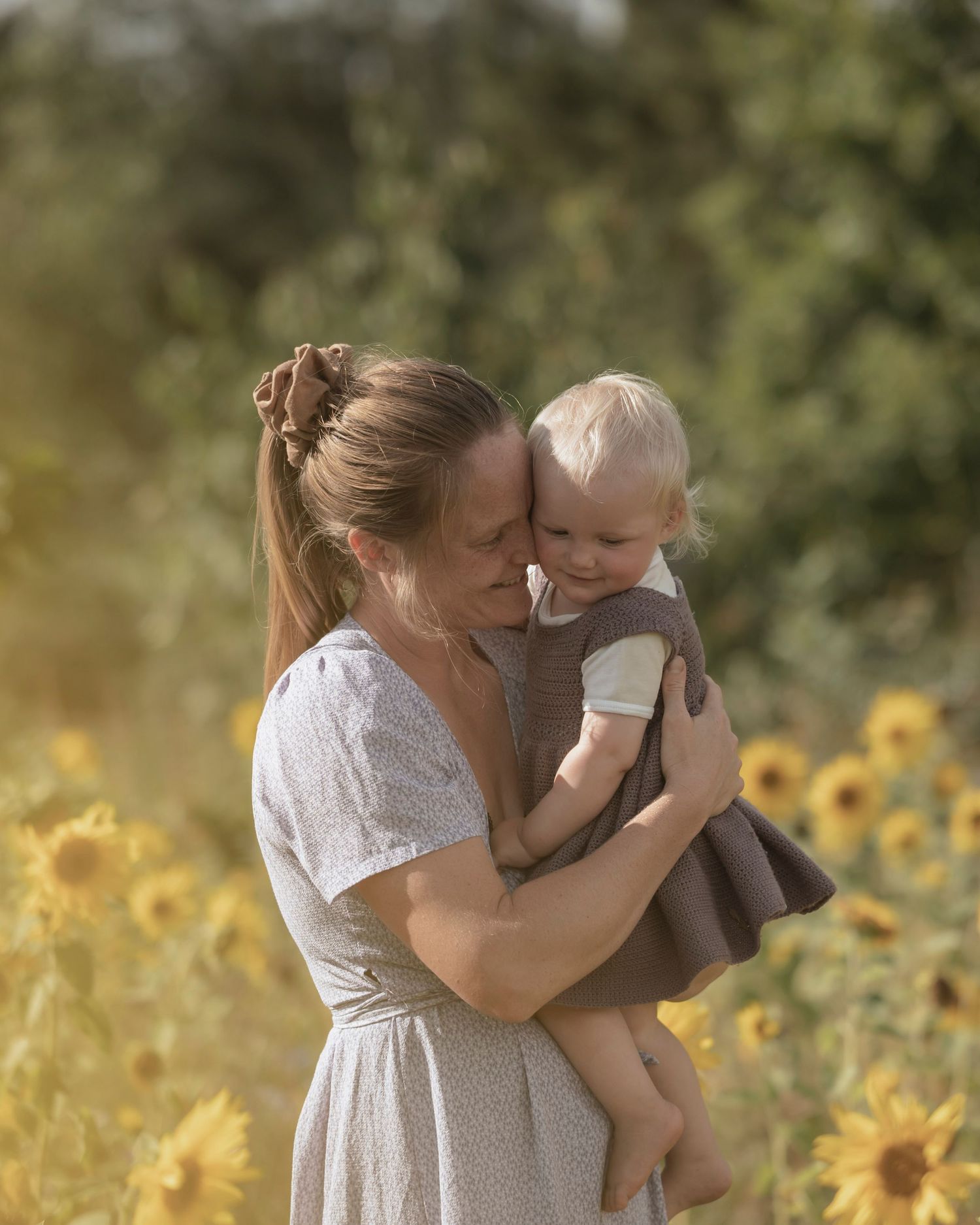 Mor og børn under familiefotografering i en blomstrende solsikkemark.