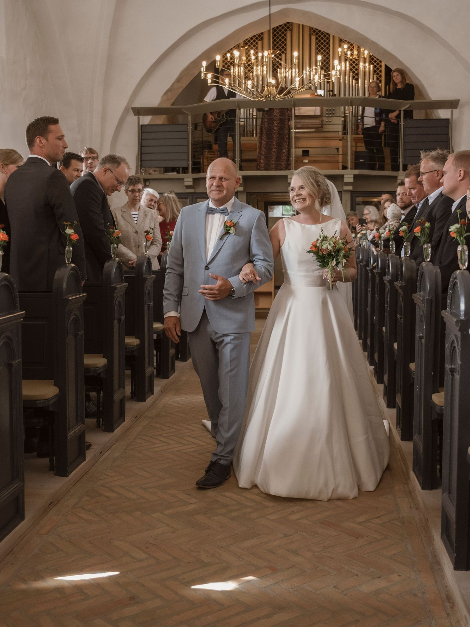 Bride and groom walking down the aisle of a historic church surrounded by wedding guests during their ceremony.