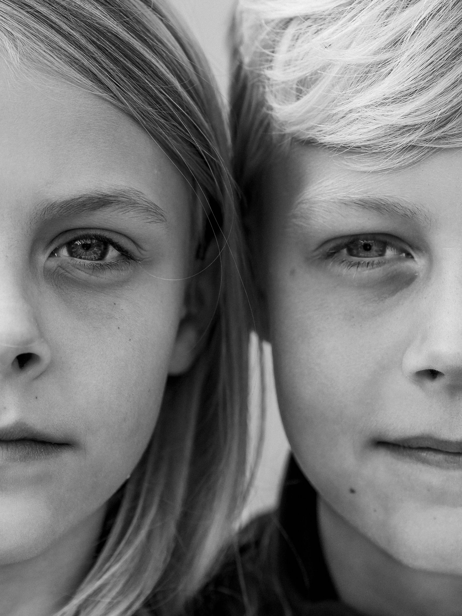 Black and white close-up portrait of two fair-haired children side by side, showing detailed facial features.