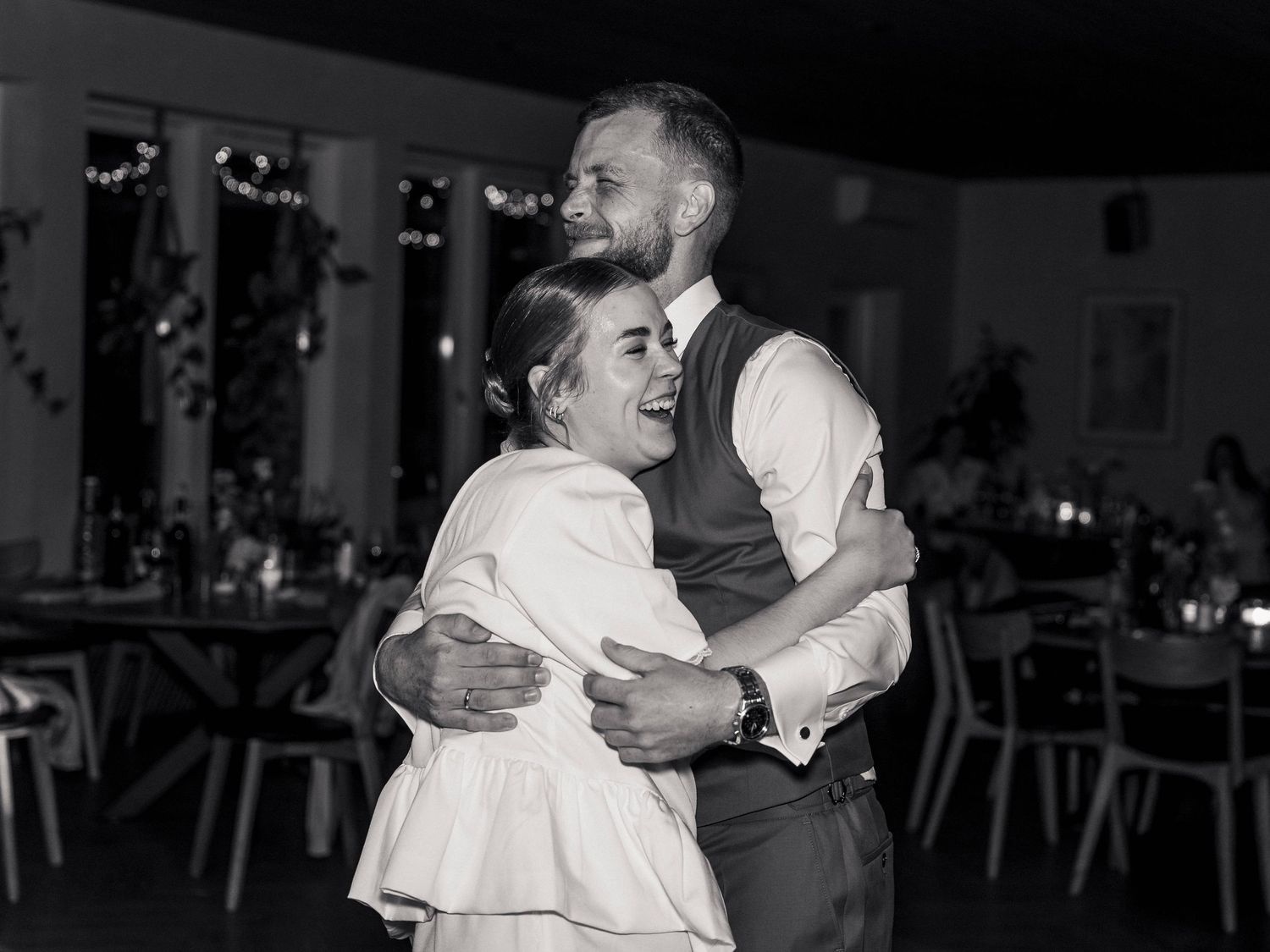 Black and white photo of a couple sharing a romantic dance embrace at a wedding reception venue.