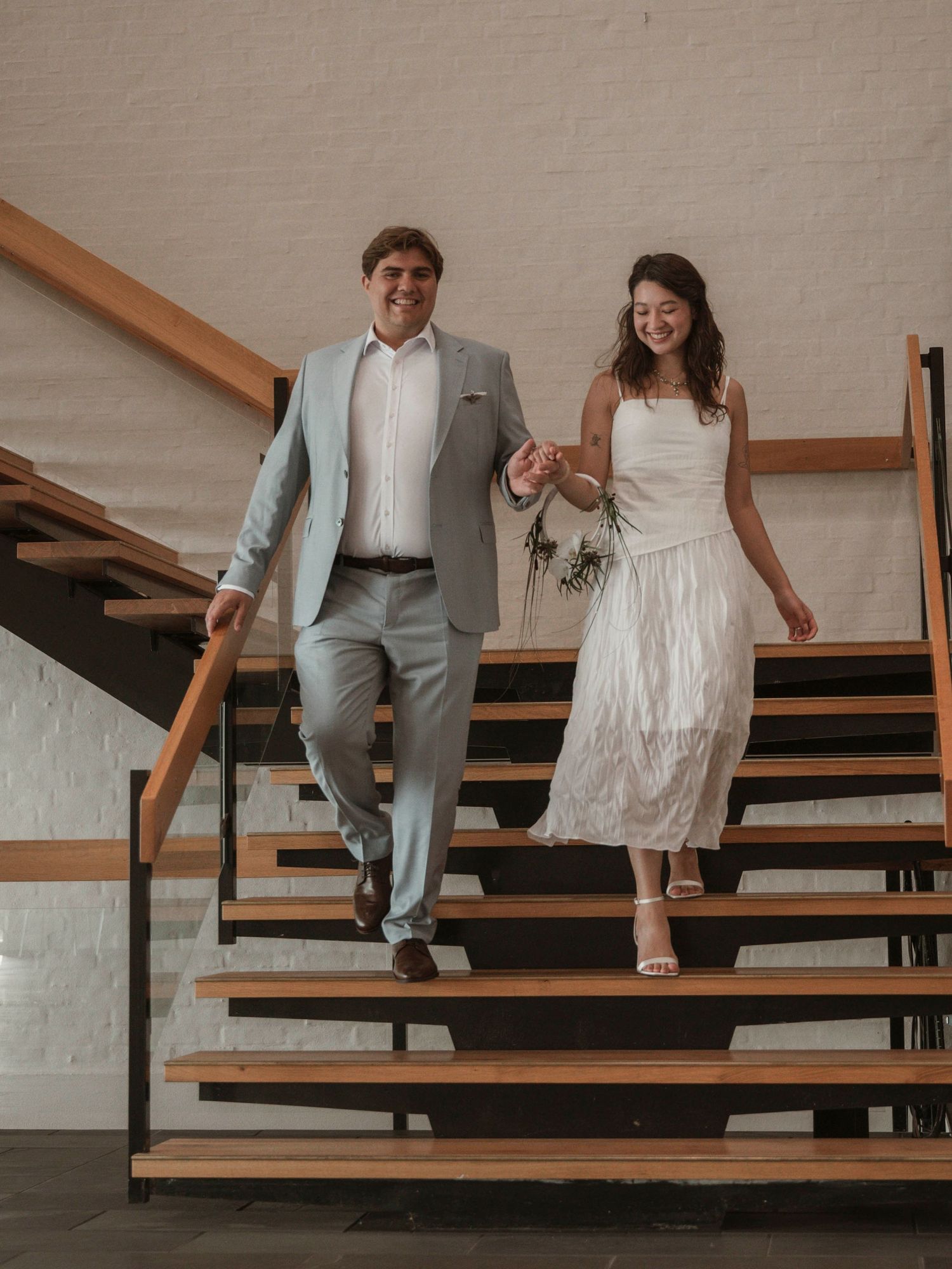 Brautpaar geht Hand in Hand die Treppe des Rathauses Ringkøbing hinunter bei einer Hochzeitsfotografie in Dänemark.