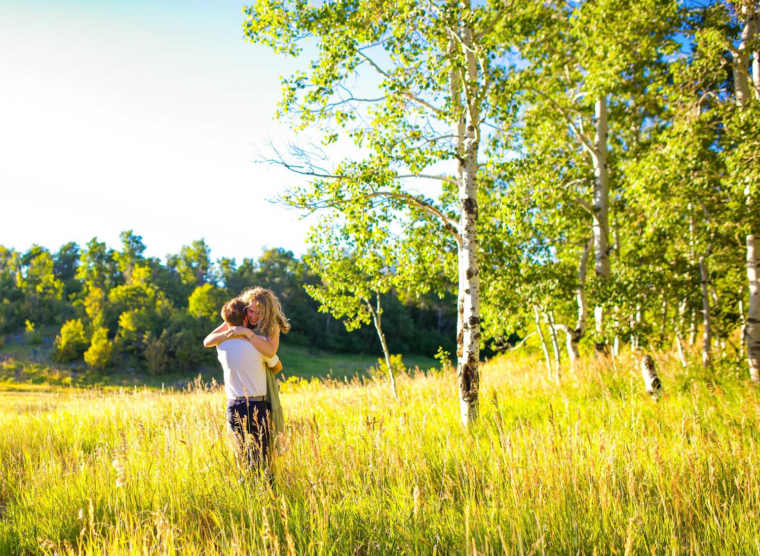 A tender embrace captured in a sunlit meadow with aspen trees and golden grass in Provo, Utah
