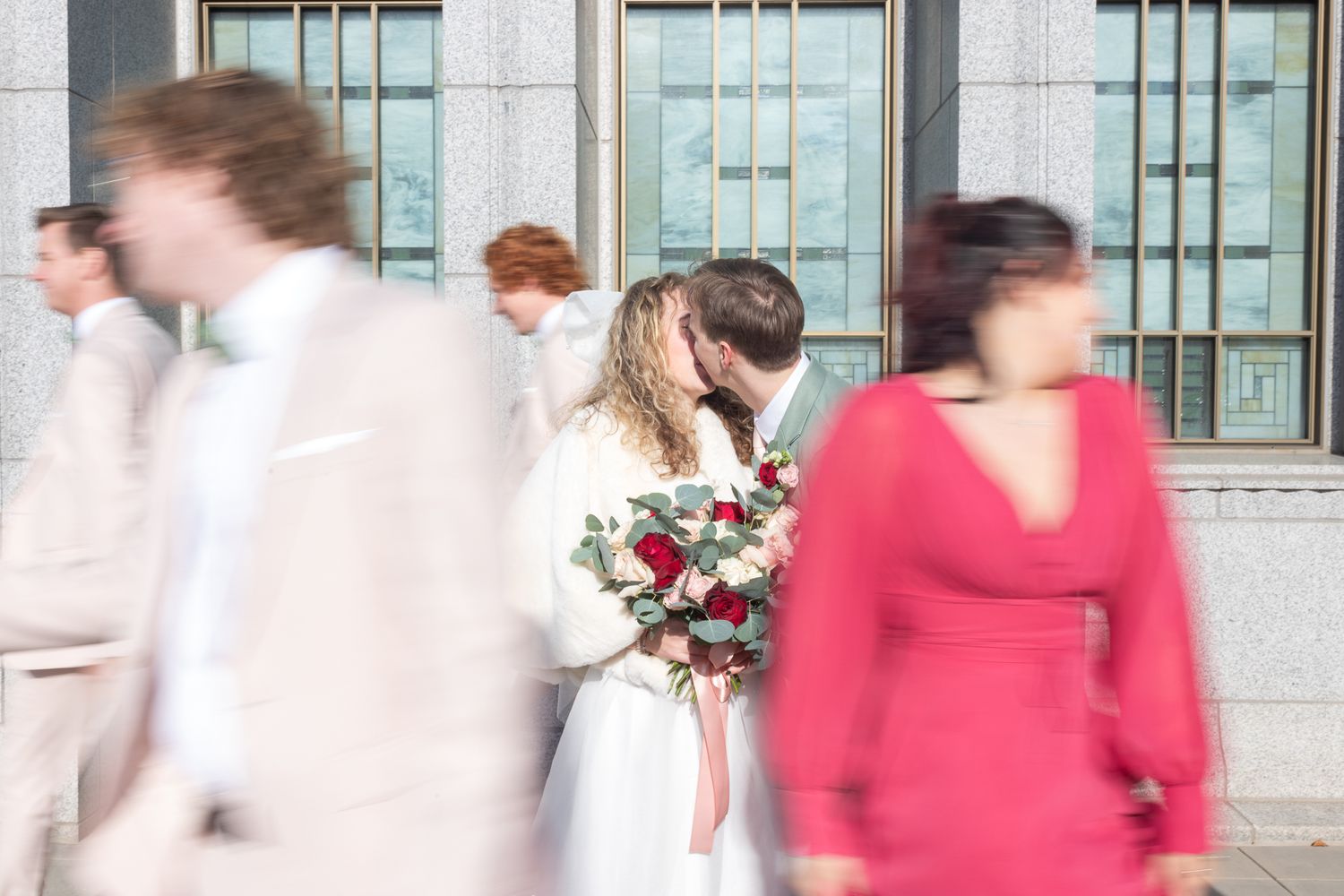 Motion blur captures wedding party movement in hallway with white dress and red accents.
