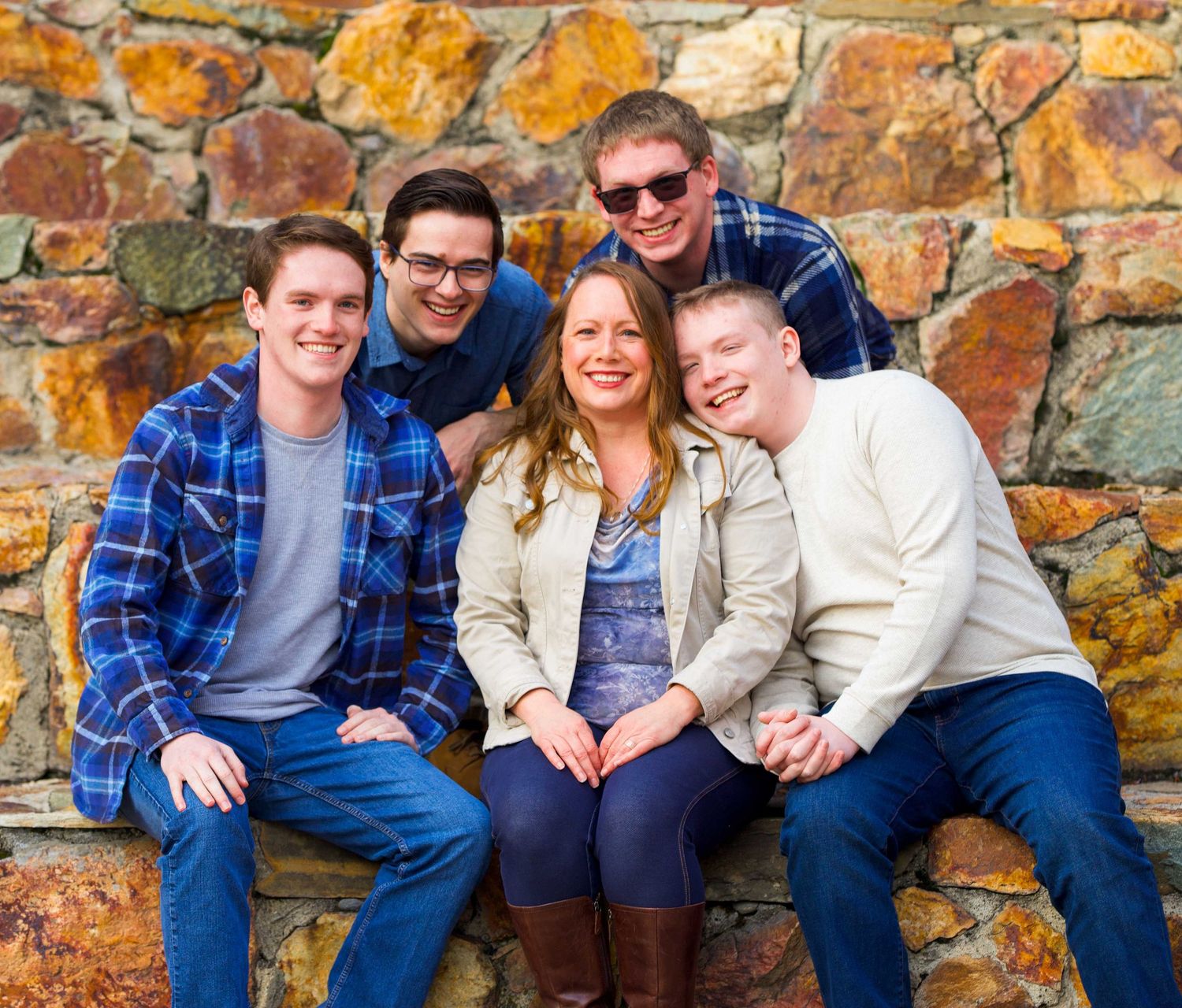 Group poses together on stone wall wearing coordinated blue and white casual outfits in outdoor portrait.