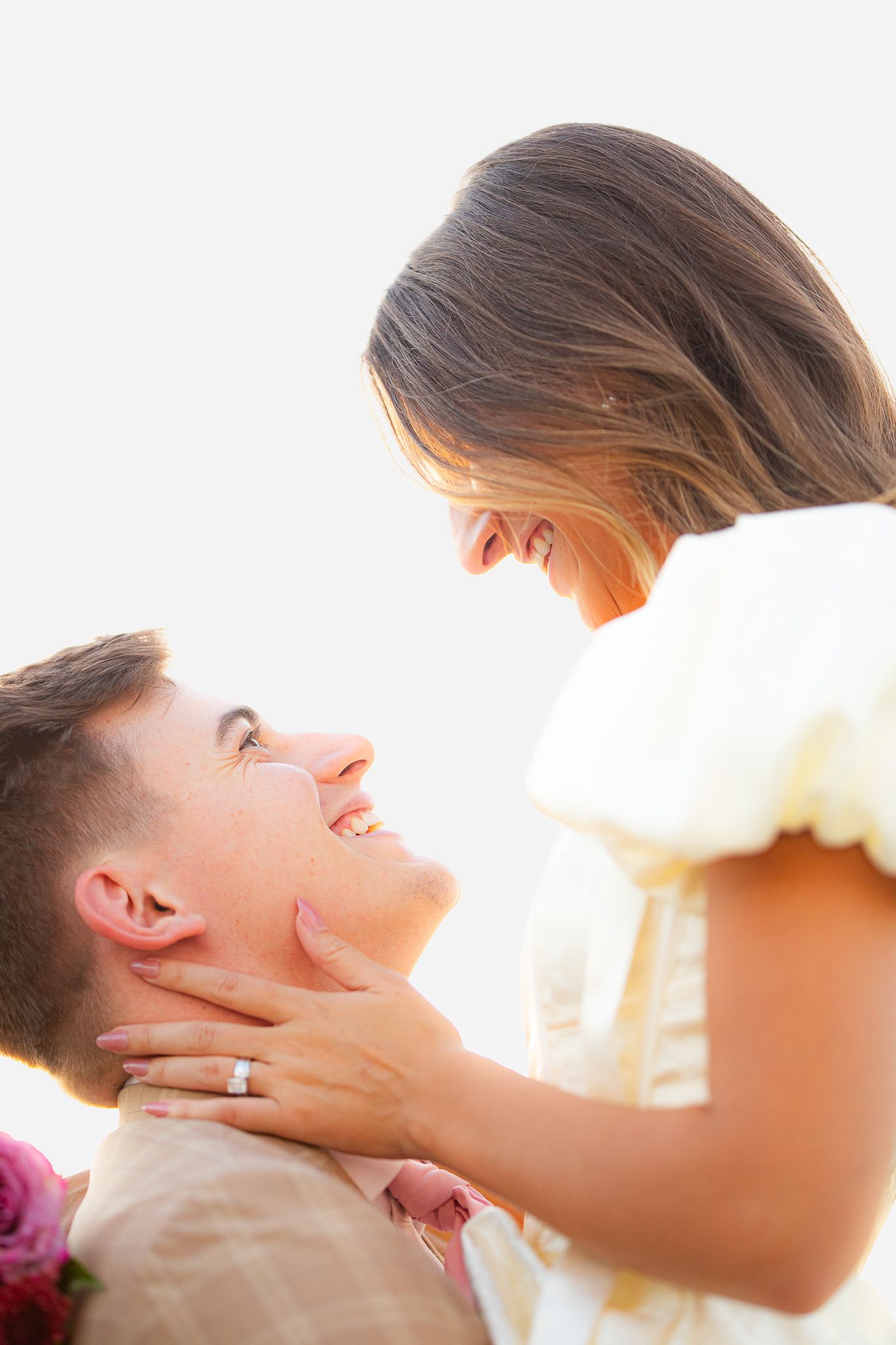 A couple shares an intimate moment during their wedding photoshoot in warm sunlight.