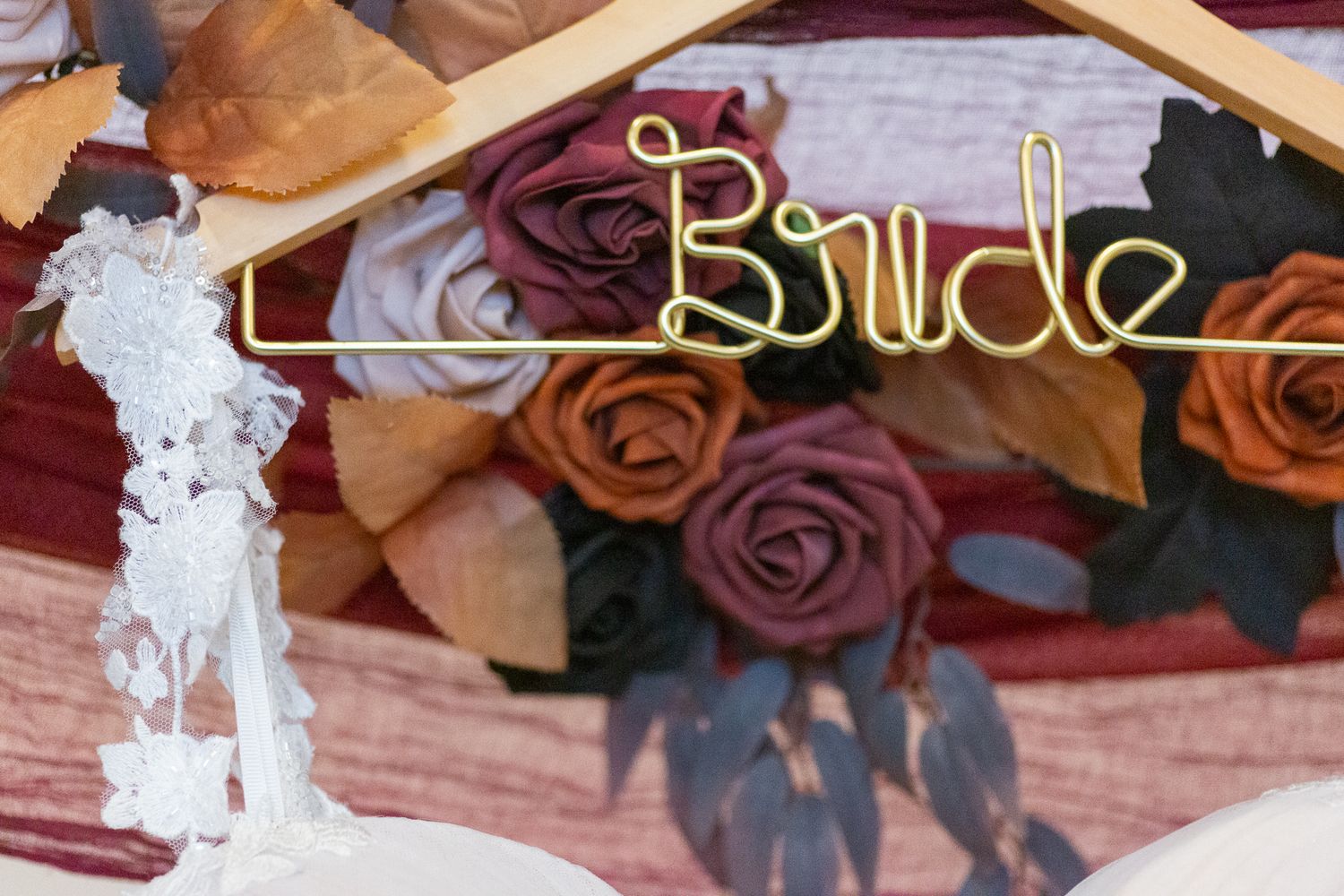 Wooden hangers displaying elegant wedding dresses with floral and bow details in a boutique setting.