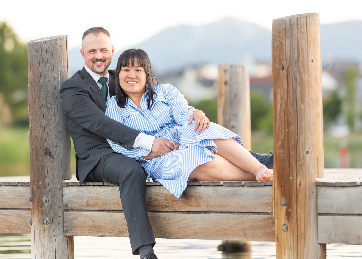 A couple poses together on a wooden dock during a photo session.