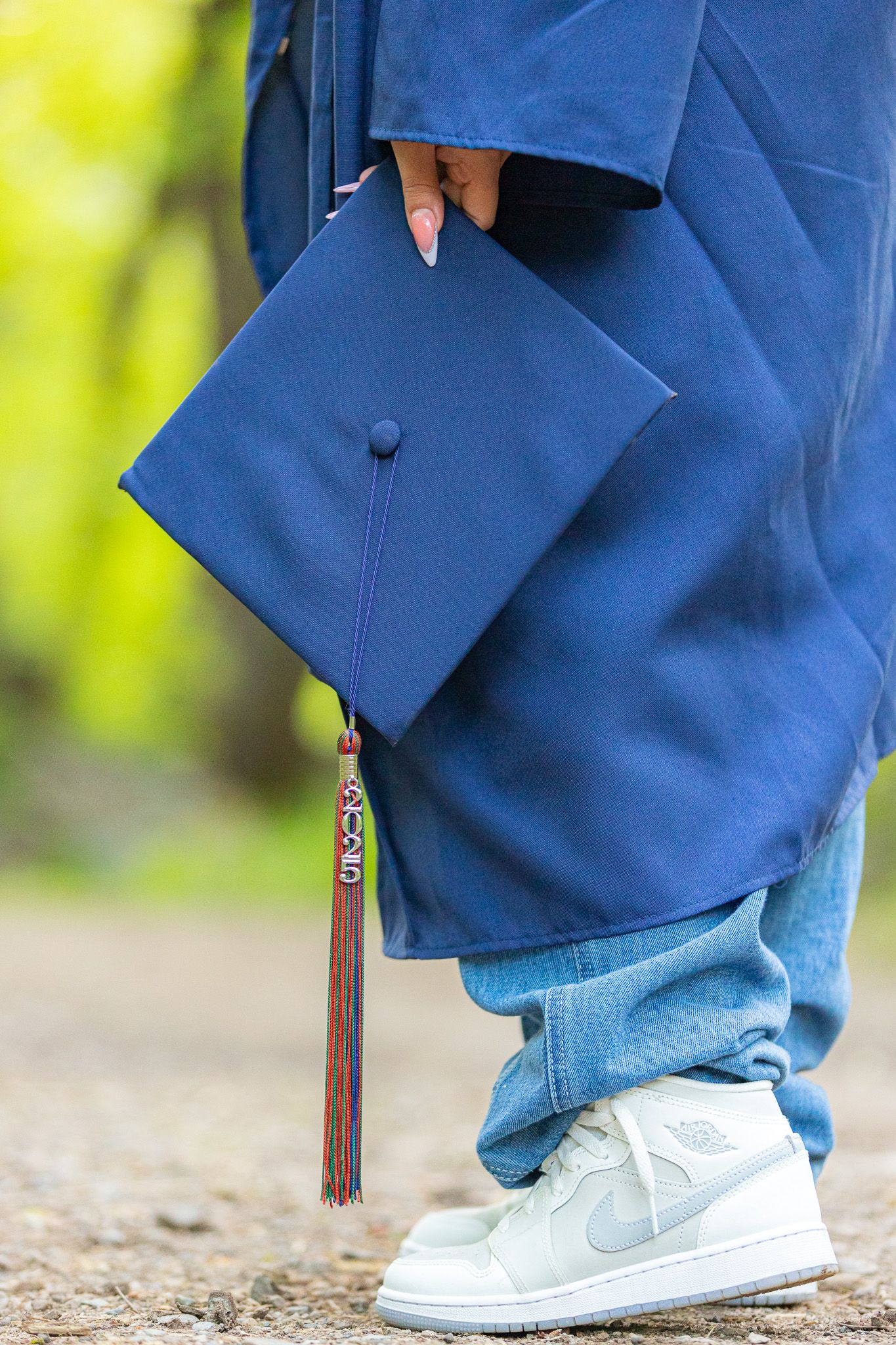 Close-up view of blue graduation cap and tassel with white sneakers during graduation session with Fergman Photography.