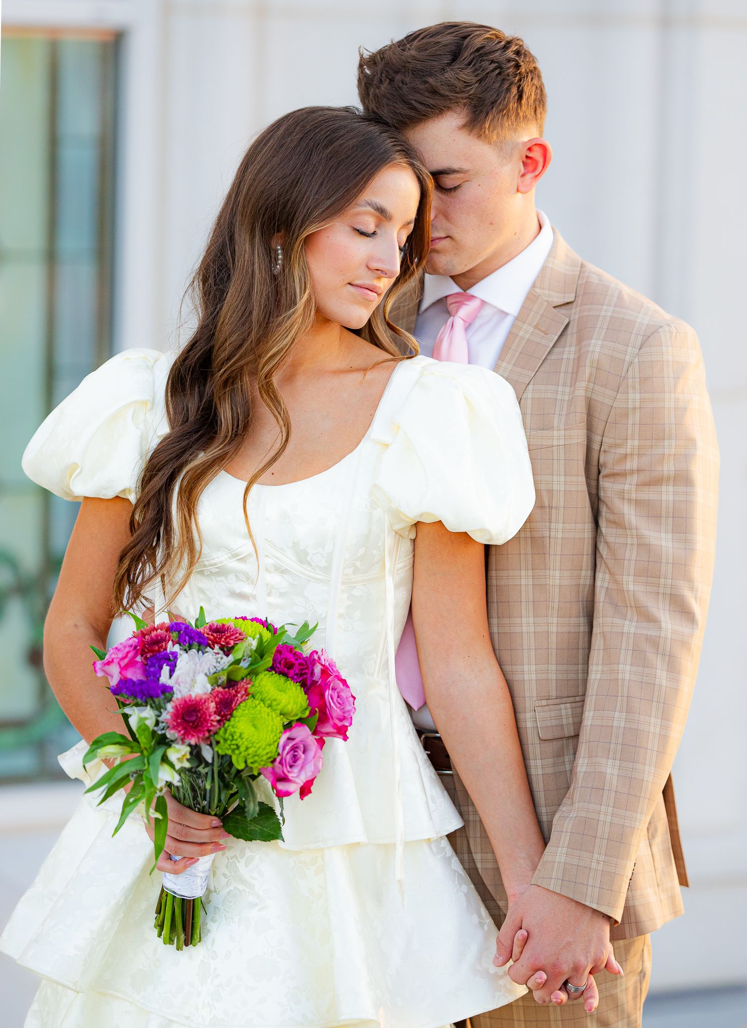 Romantic couple photos with colorful bouquet against white columns.