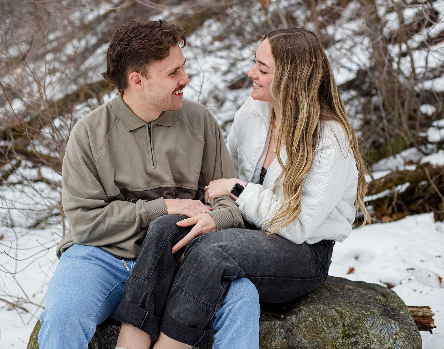 Couple enjoying playful moments together in a snowy winter setting.