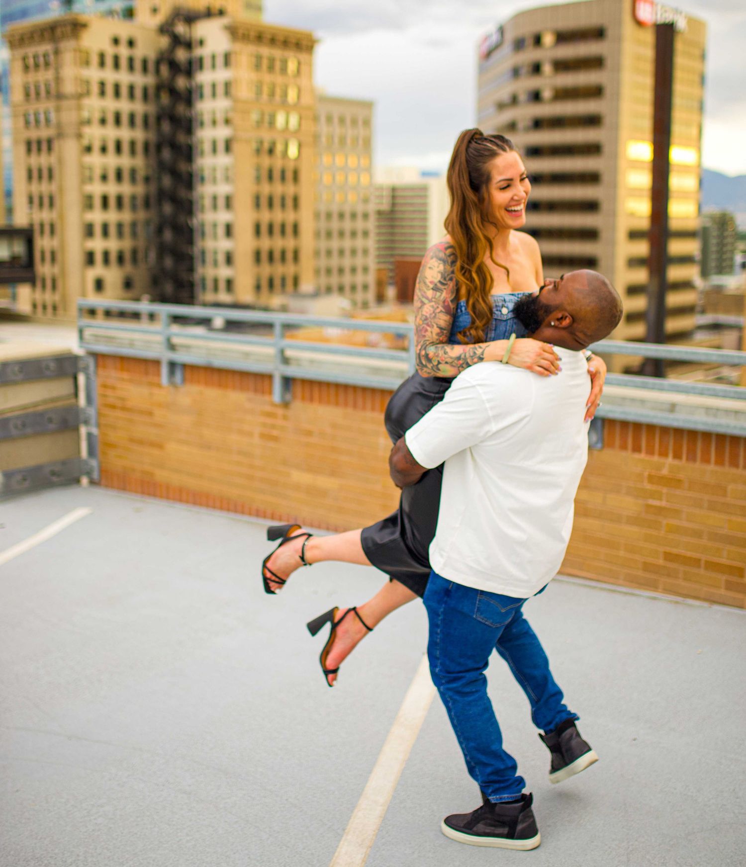 Romantic rooftop moment with city buildings visible in the golden hour light.