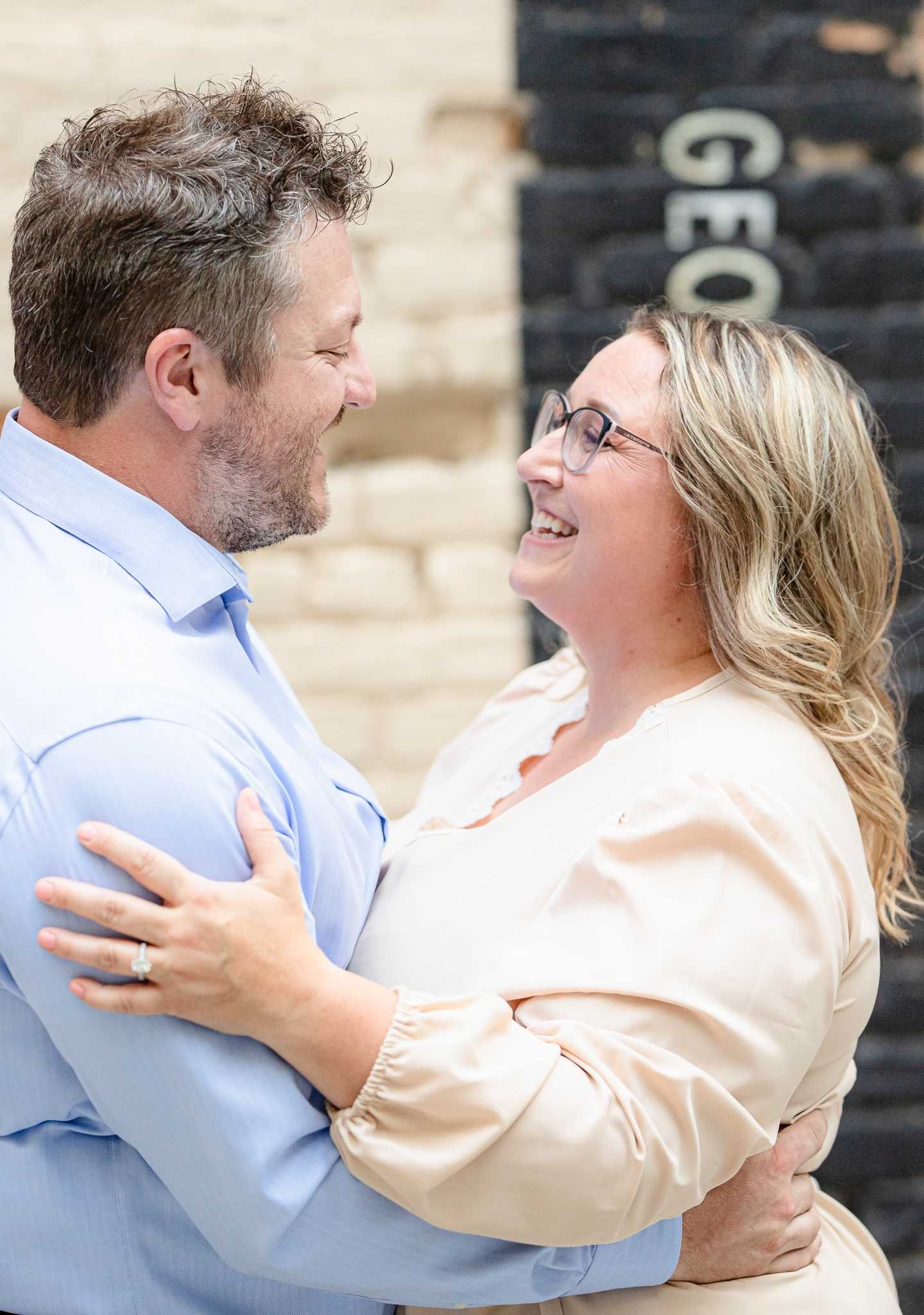 Happy couple sharing a tender moment against brick wall.