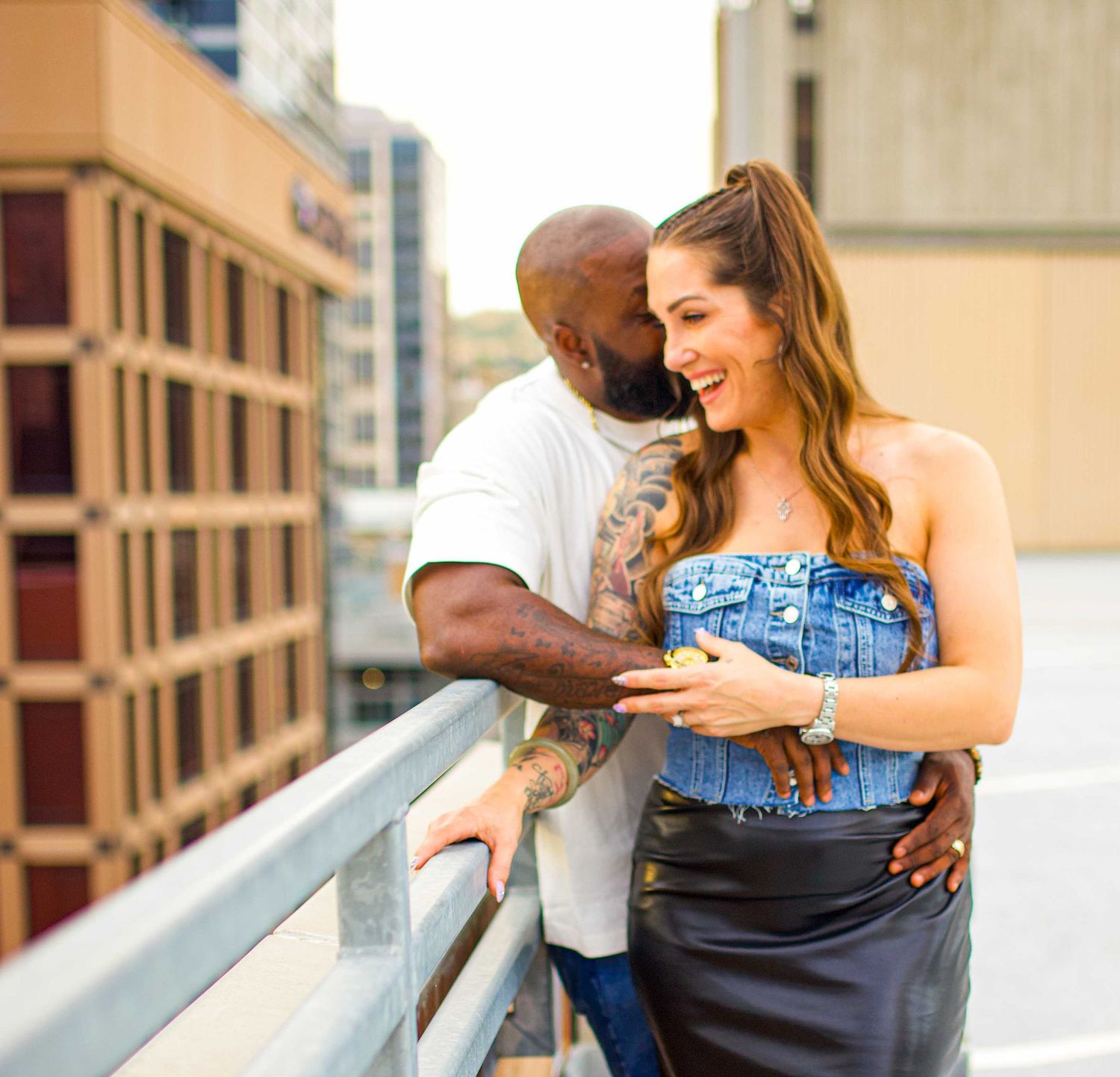 Tender embrace shared on an urban rooftop with brick buildings in the background.