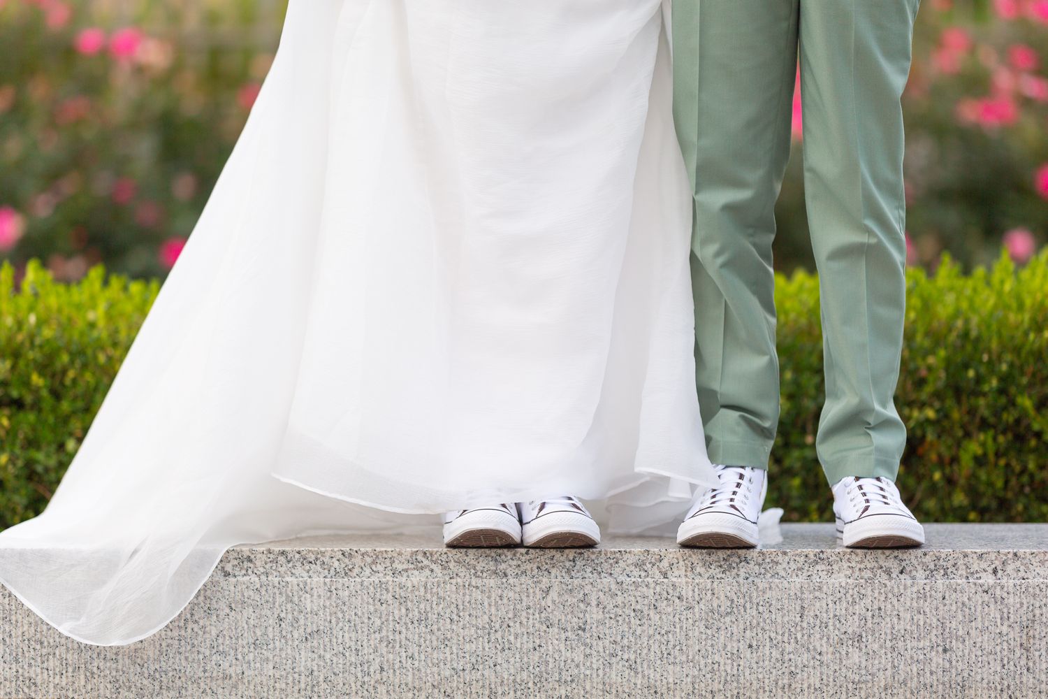 Artistic detail shot of bride and groom's shoes with flowing wedding dress.