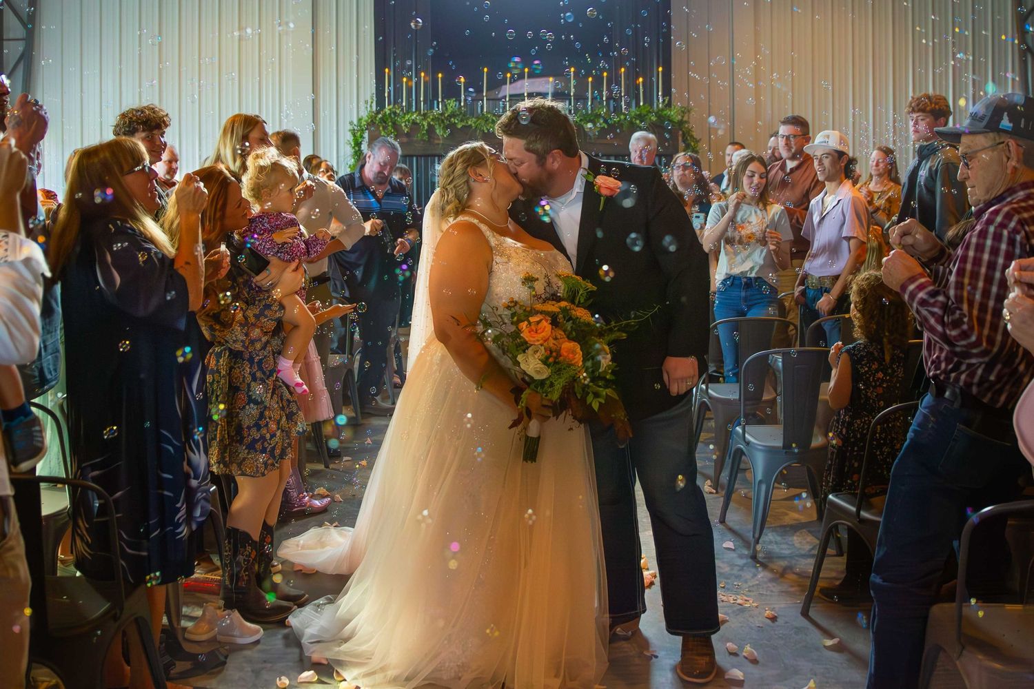 Wedding couple sharing their first dance surrounded by guests at an indoor reception.