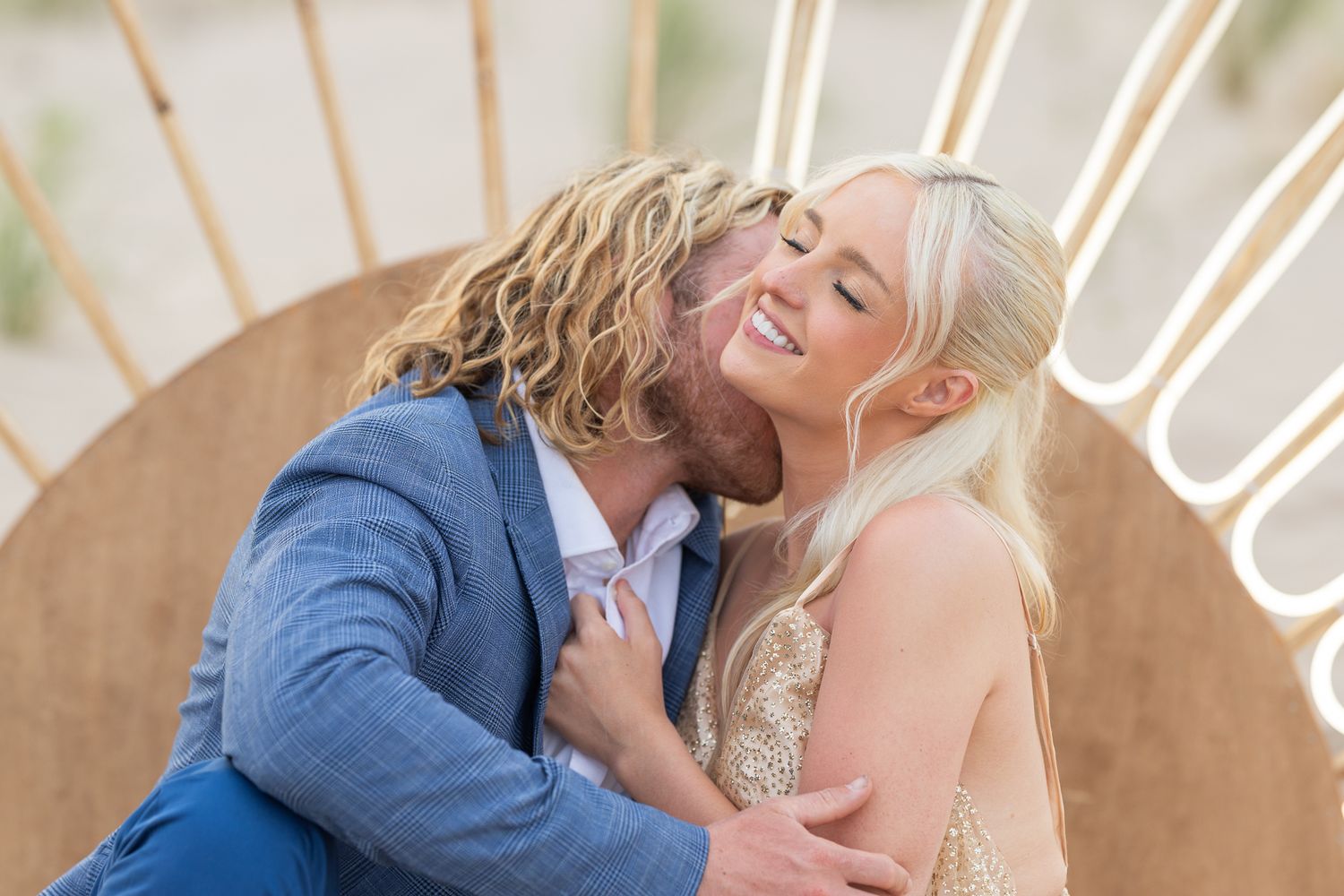 Couple shares joyful embrace against decorative background during engagement or wedding shoot.