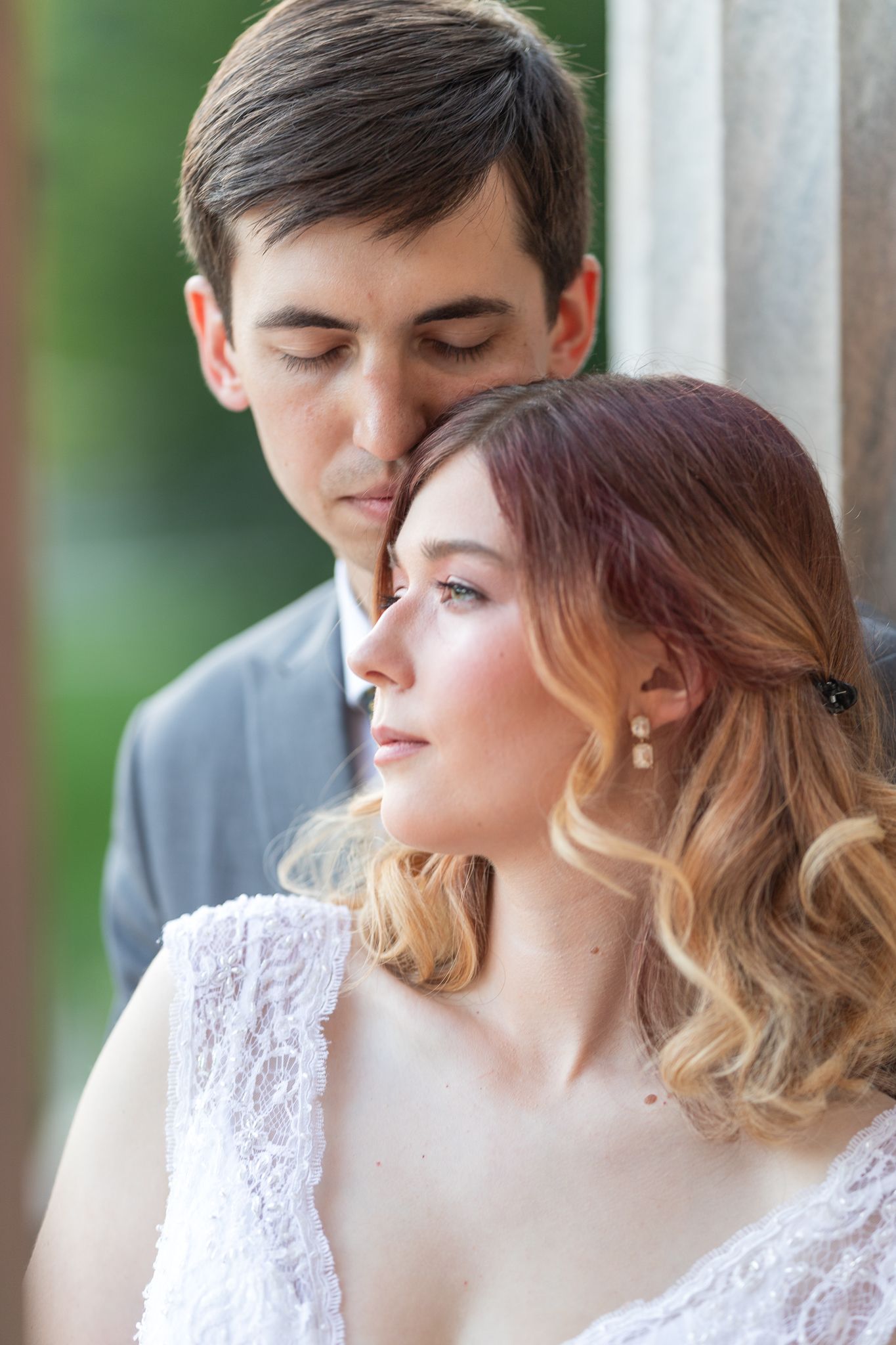 Couple in formal attire shares tender moment during outdoor portrait session.