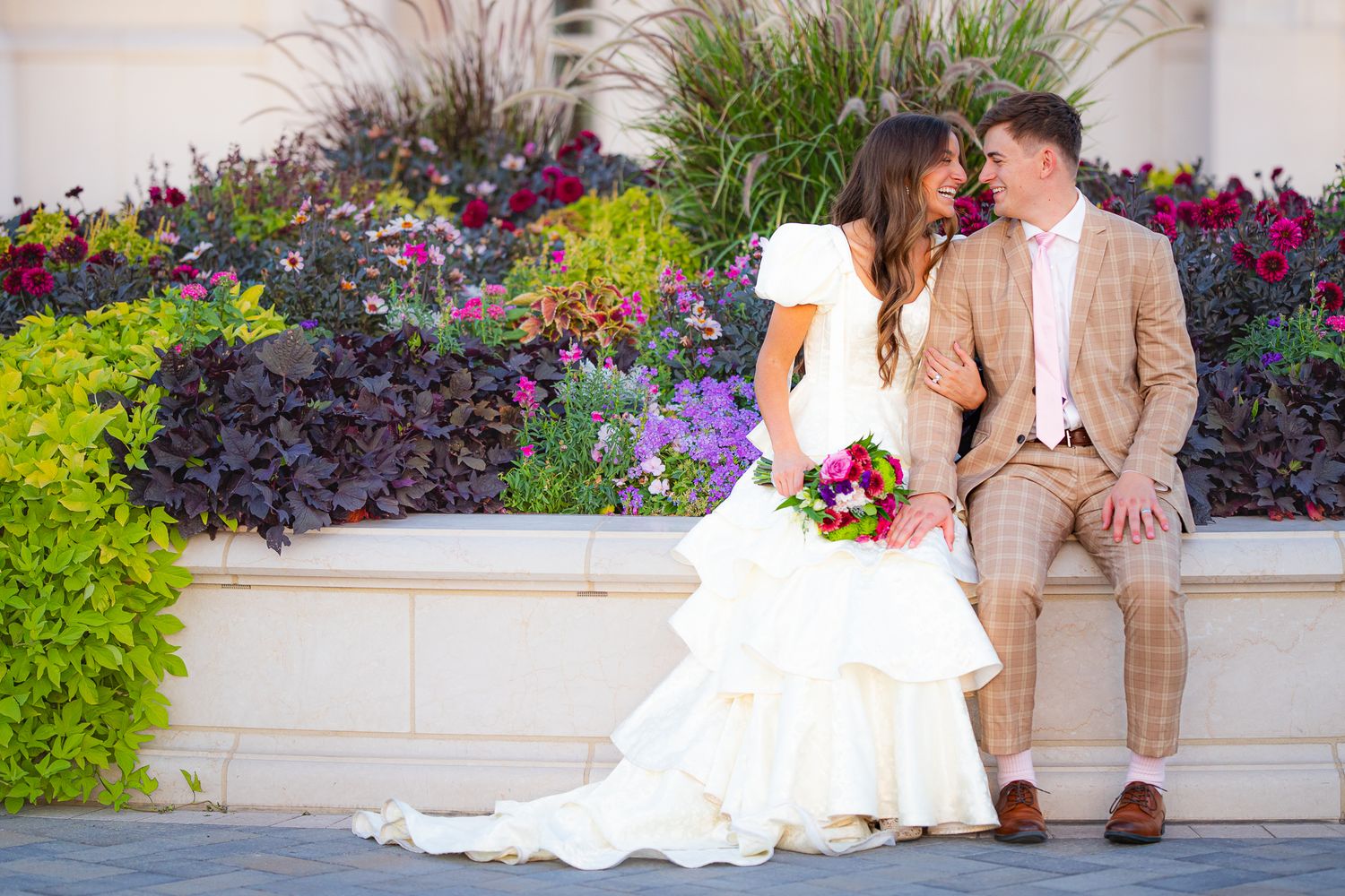 Wedding portraits with couple sitting among colorful flower gardens.