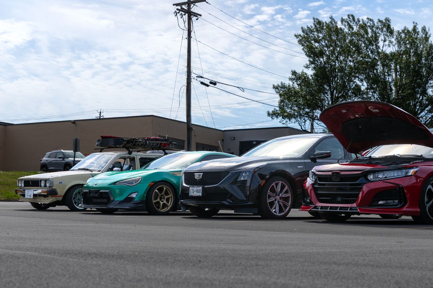 Row of performance and luxury cars parked at an outdoor dealership or car meet showing various colorful vehicles.
