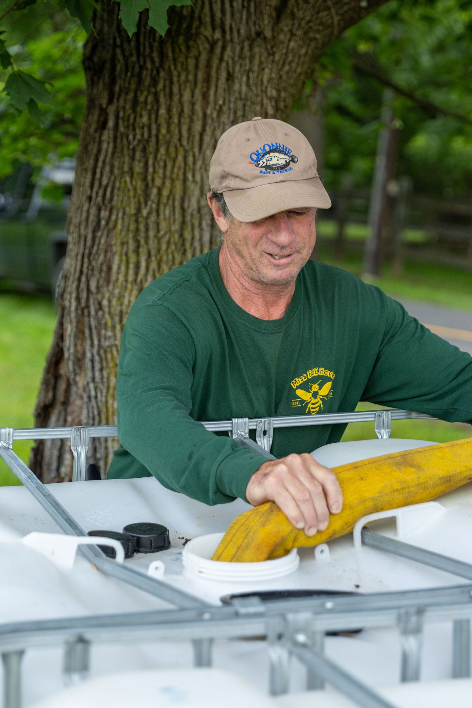 Firefighter in green shirt and baseball cap working with equipment outdoors.
