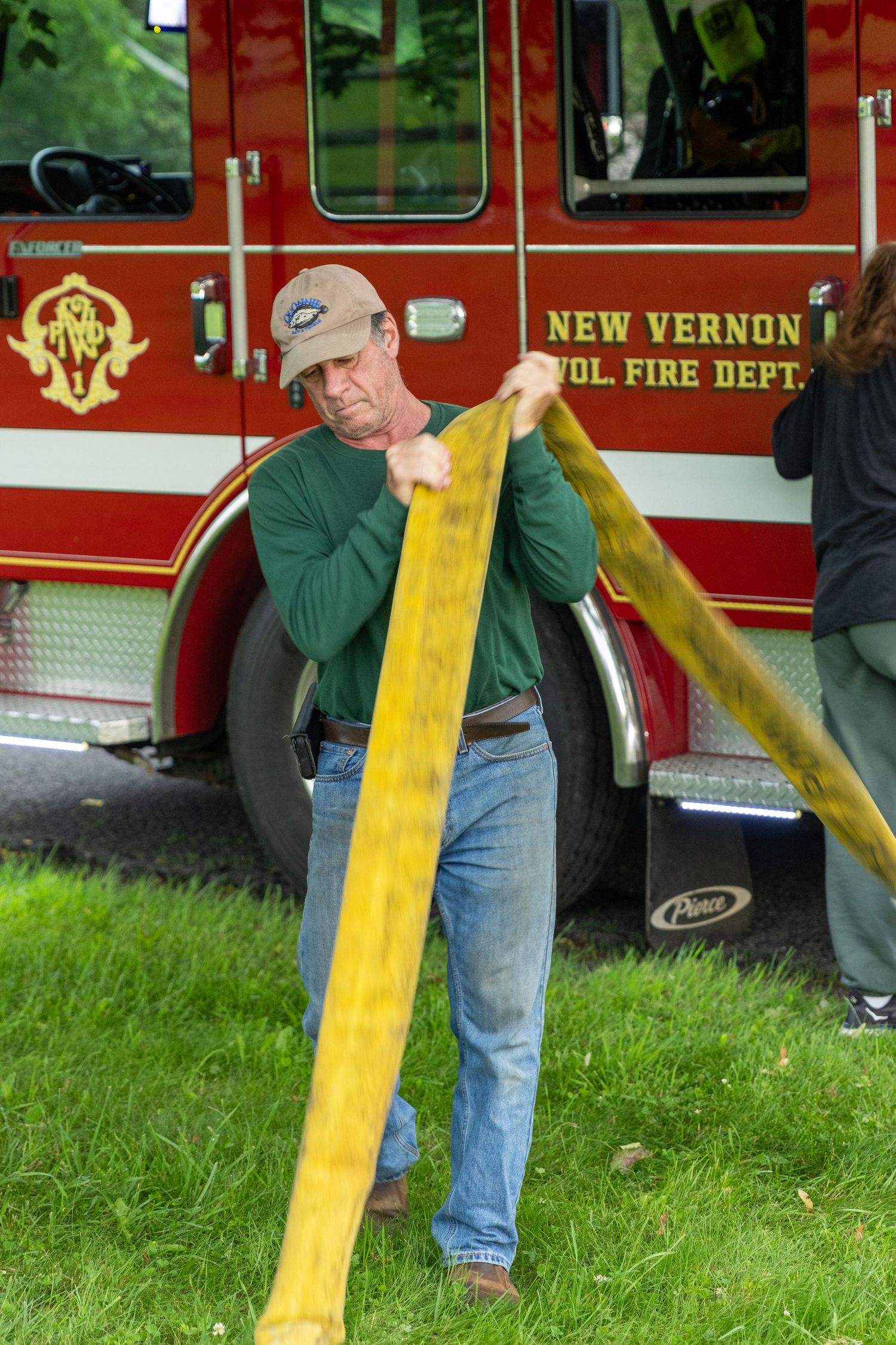 Firefighter handling yellow fire hose near New Vernon Fire Department truck.