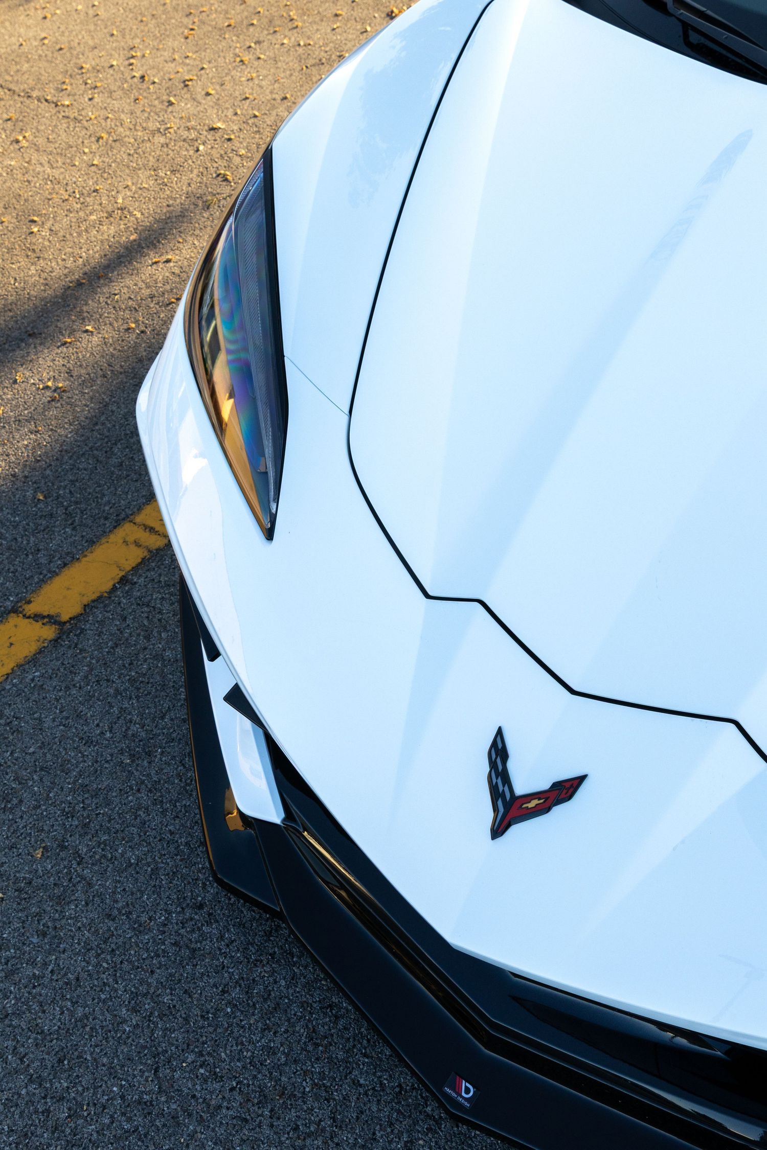 Close-up view of a white Chevrolet Corvette C8 hood featuring angular body lines and black accents.