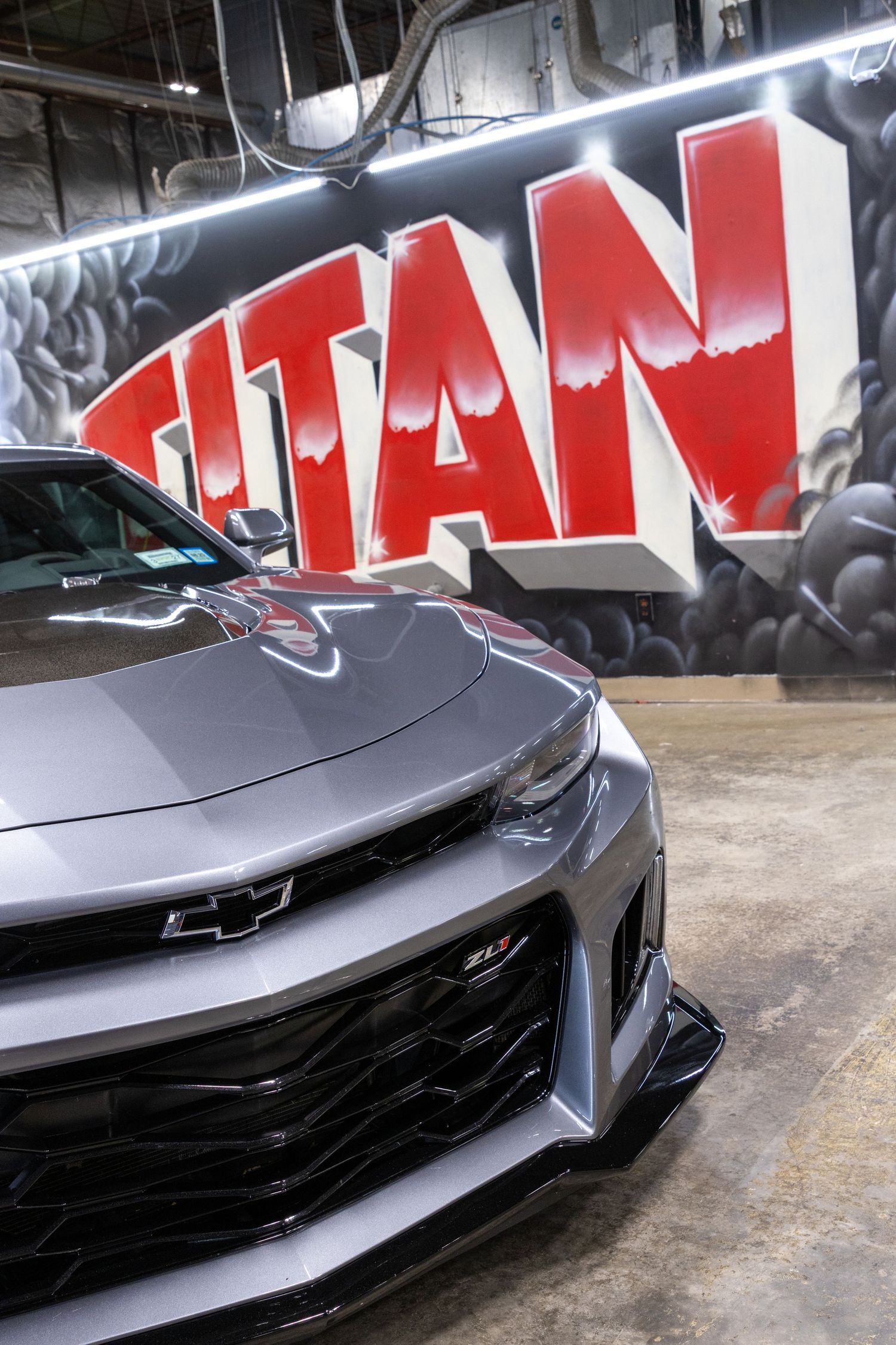 Close-up sequence showing the sleek front end details of a grey sports car with aggressive styling and red lettering.