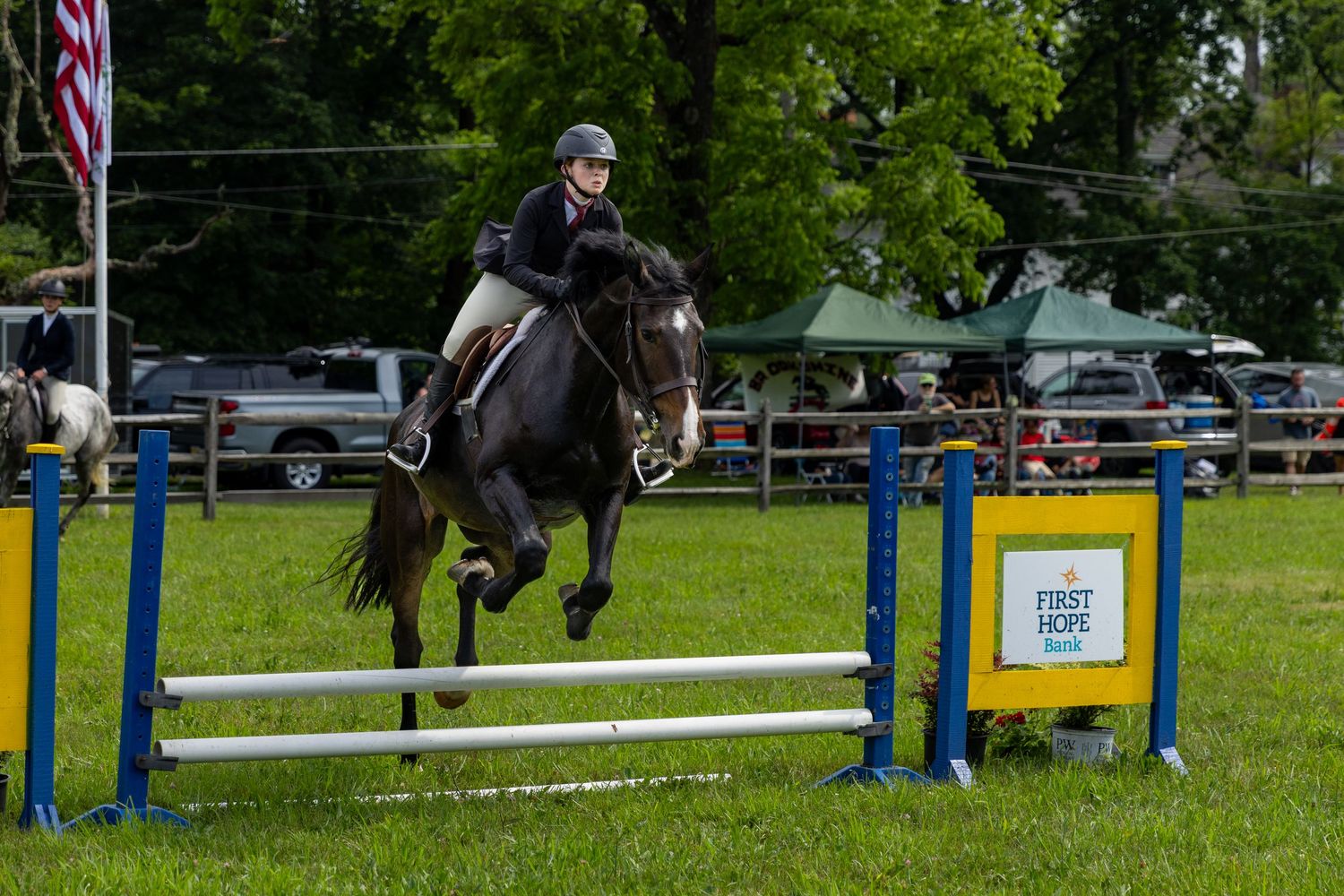 A horse and rider clearing a jump obstacle during an equestrian competition.