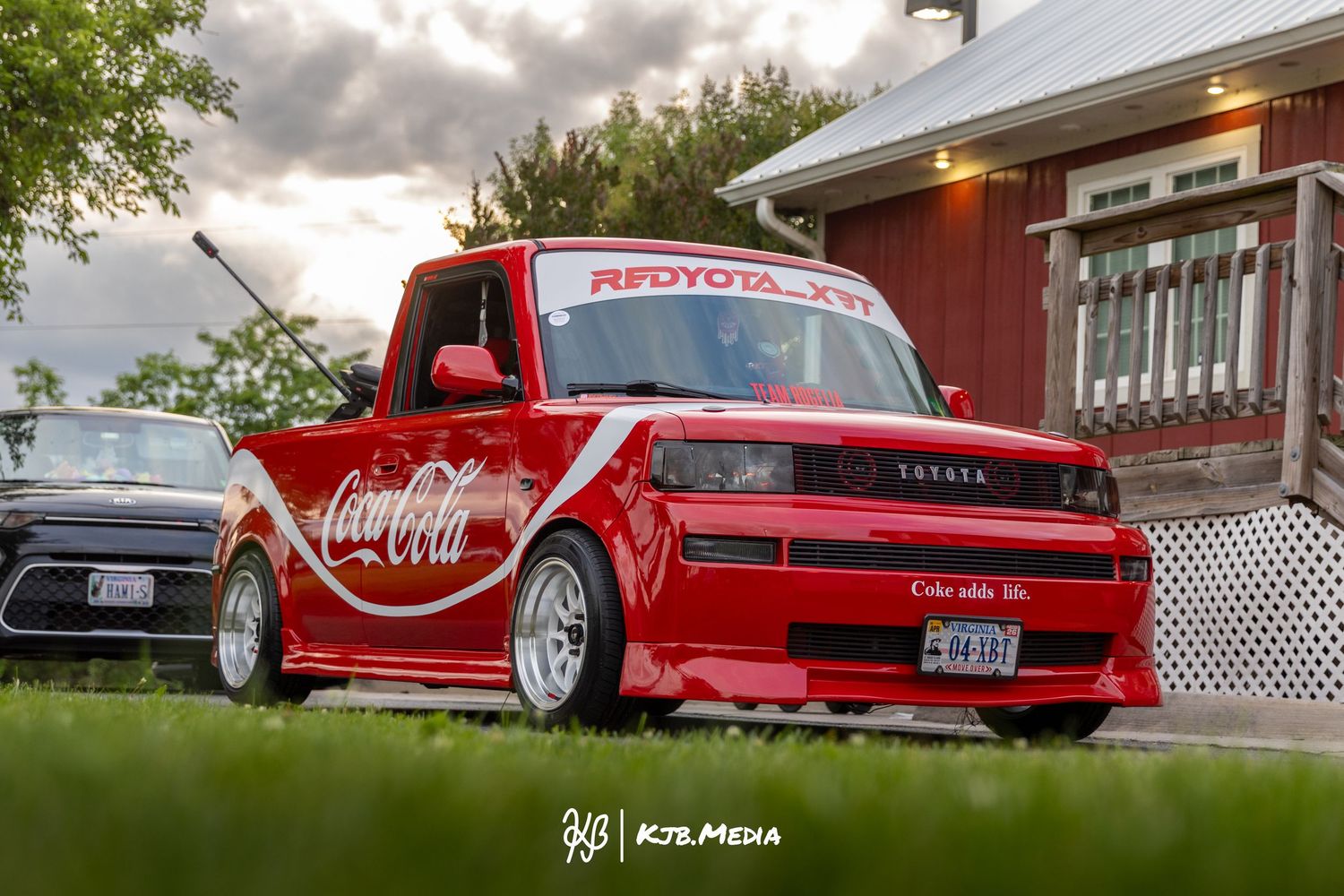 Custom lowered red truck with Coca-Cola branding photographed against residential backdrop.