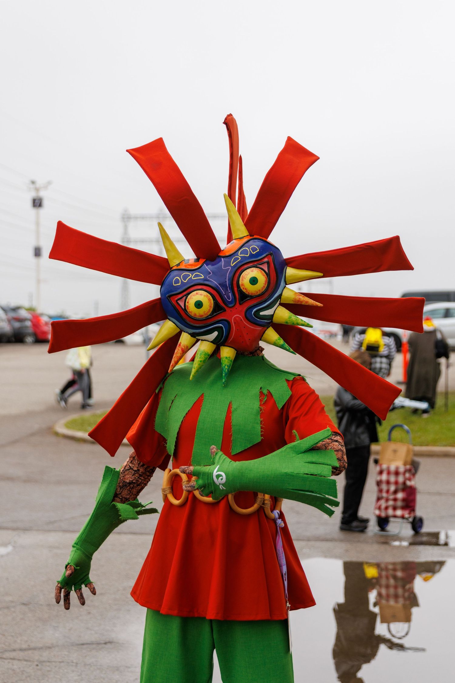 Colorful Skull Kid cosplay from Legend of Zelda Majoras Mask with vibrant red and green costume outdoors.