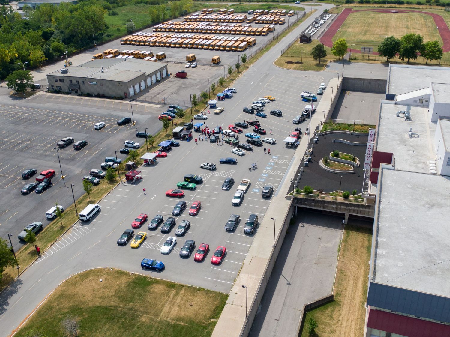 Aerial drone view of a parking lot with scattered vehicles and commercial buildings in a business district.
