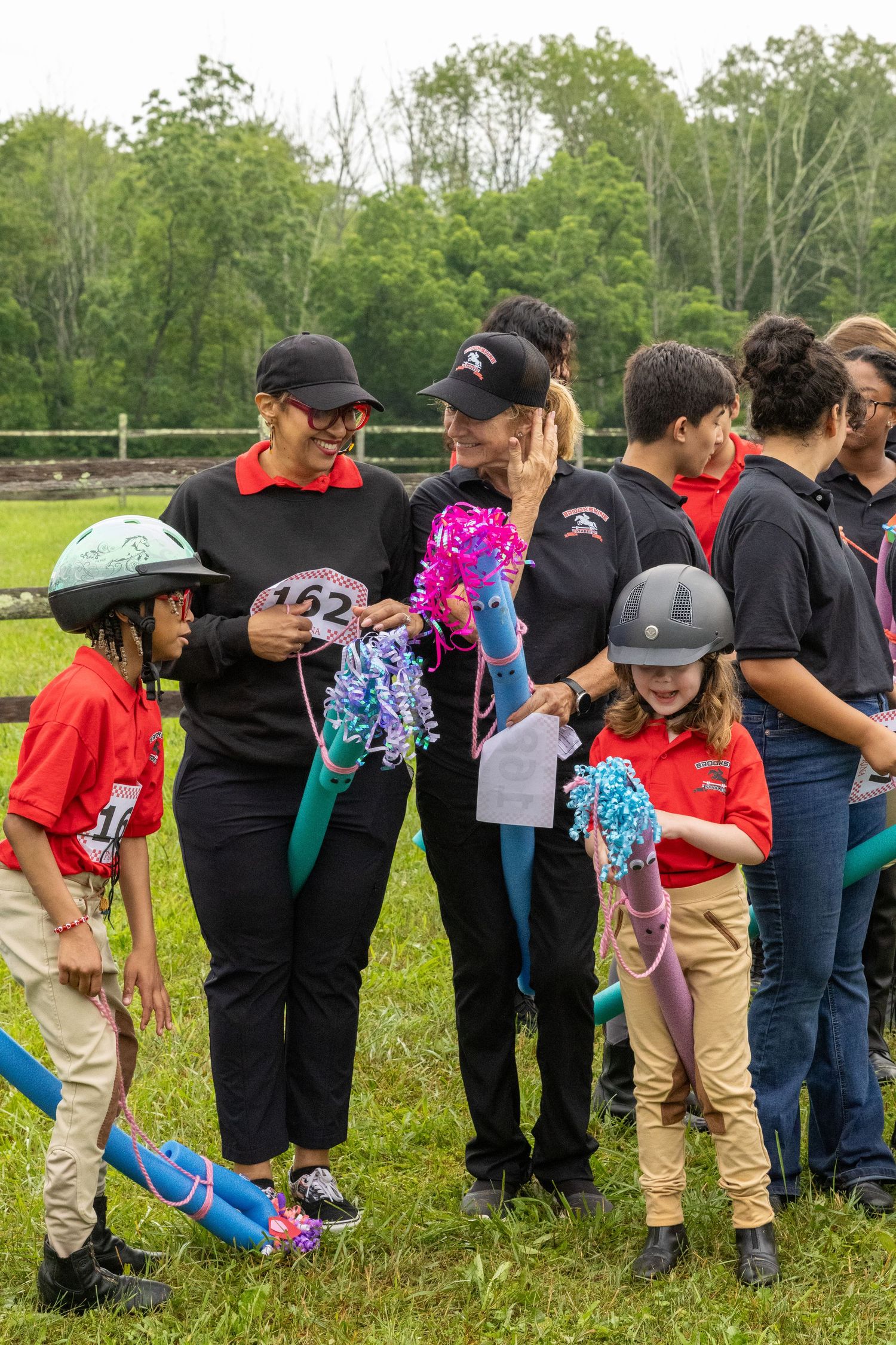 Group gathering outdoors with colorful pom poms and safety helmets.