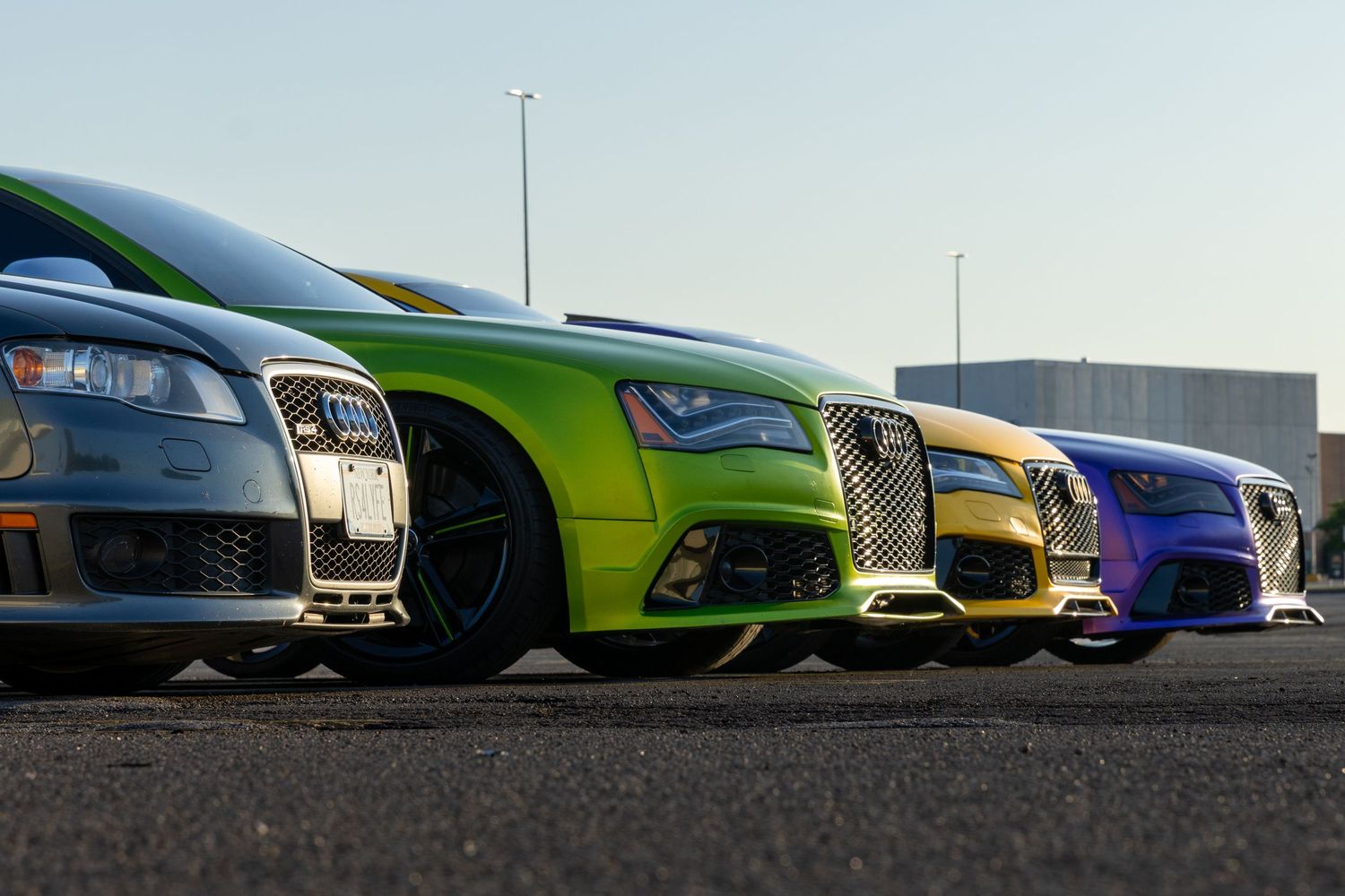 Row of colorful luxury sports cars lined up at a car meet.