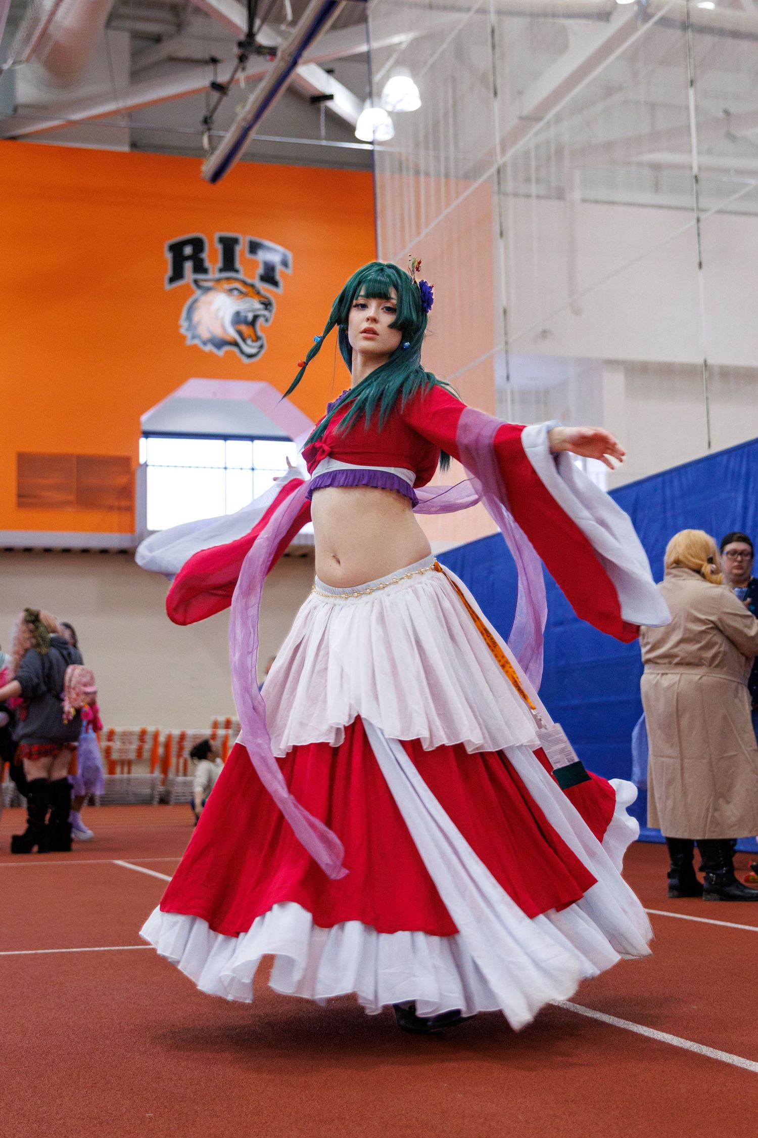 Cosplayer in red and white flowing dress with green hair spinning at RIT anime convention.