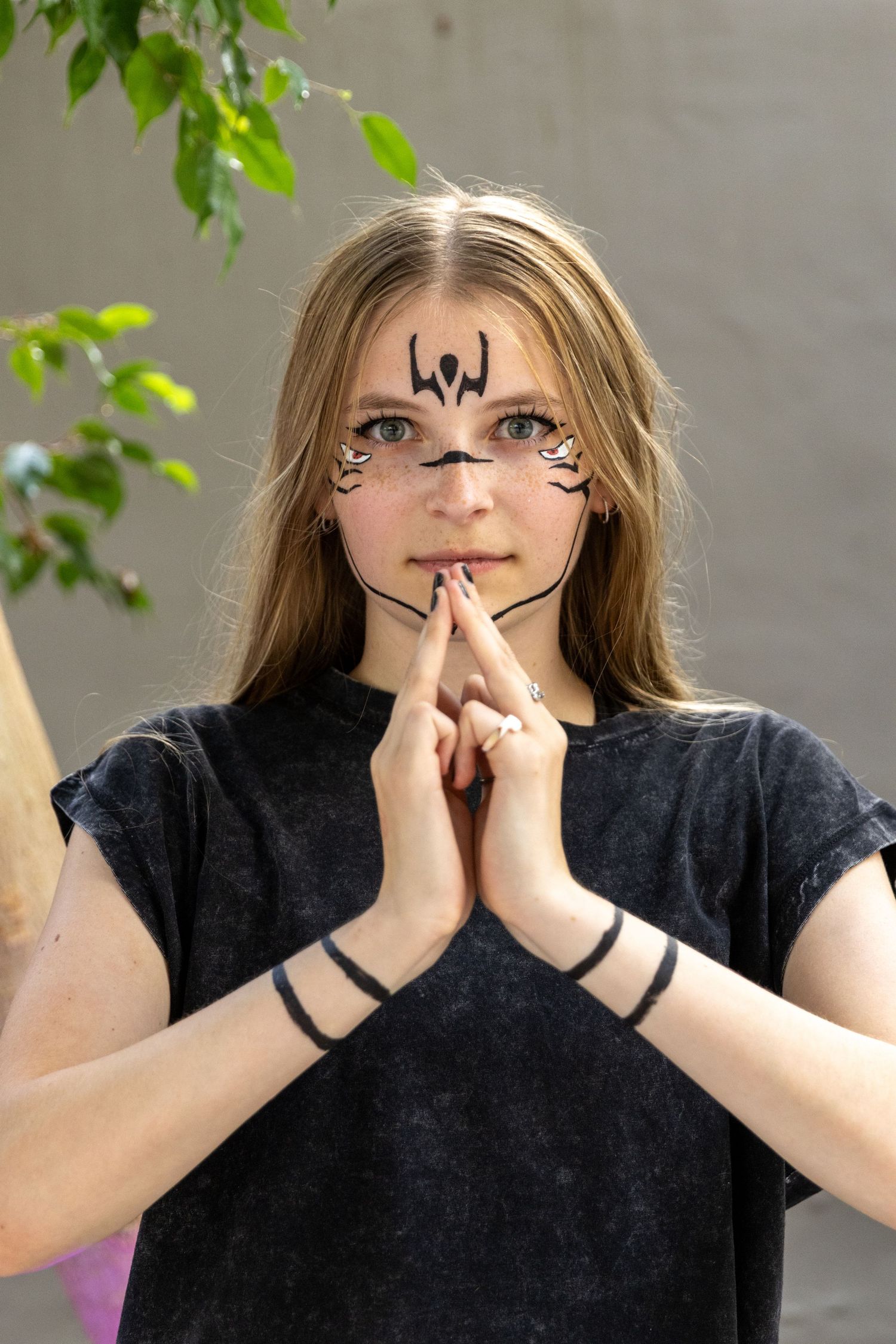 Four sequential photos showing progressive hand gestures in front of a face against a leafy green background.